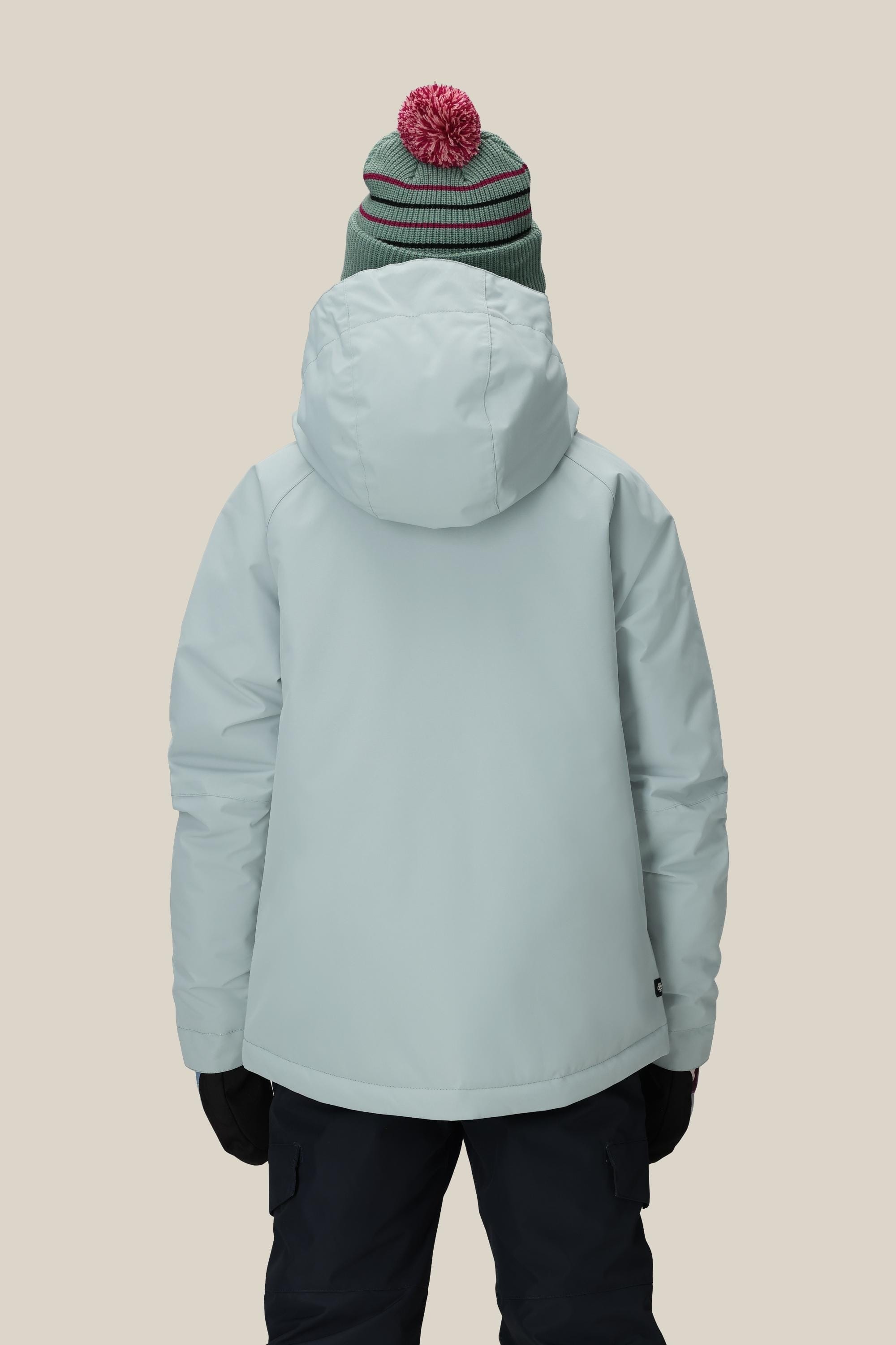 A person shown from the back against a plain beige background wears the 686 Girls Hydra Insulated Jacket in light gray, paired with black gloves, dark pants, and a green knit hat with red and white stripes and a pom-pom.