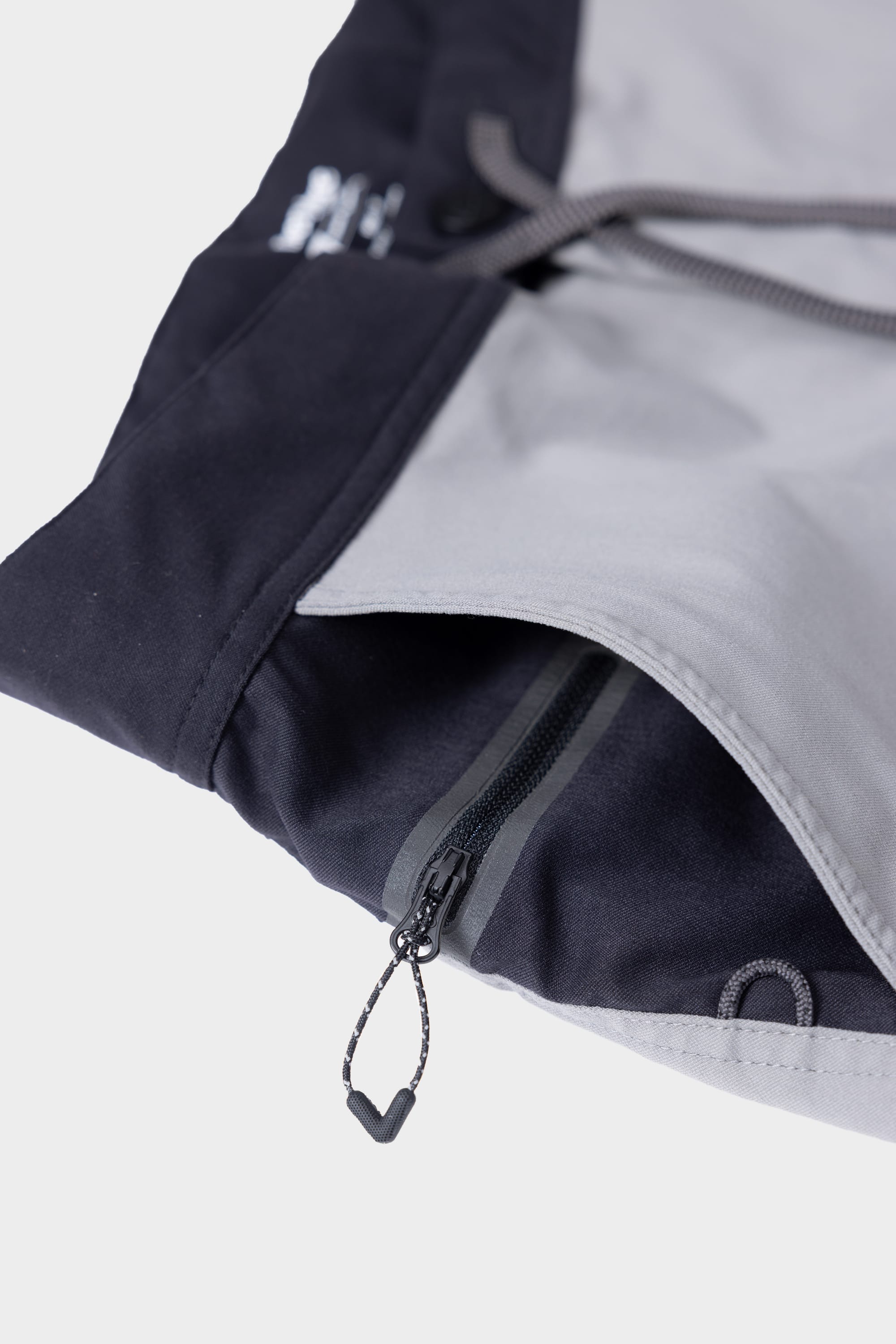 Close-up of the 686 Mens Platform Bike Pant - Slim Fit, showing grey and black fabric, a zipper pocket with a black pull, and a drawstring in the background.