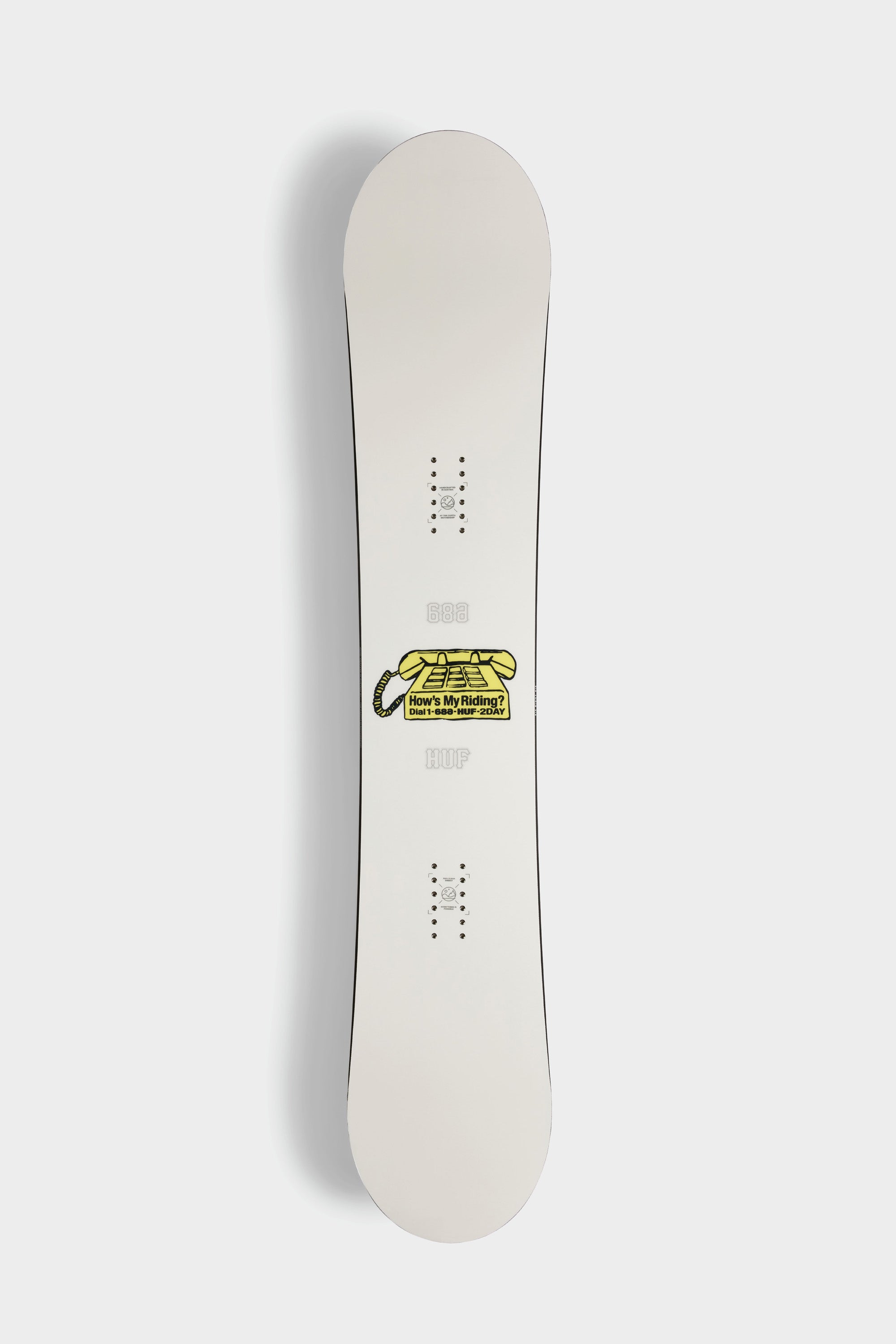 The 686 HUF Outerspace Living Snowboard by 686 features a white deck with a central yellow snake graphic and HERES MY HANDLE text. Its versatile all-terrain camber and freestyle shape make it perfect for freeriding adventures.