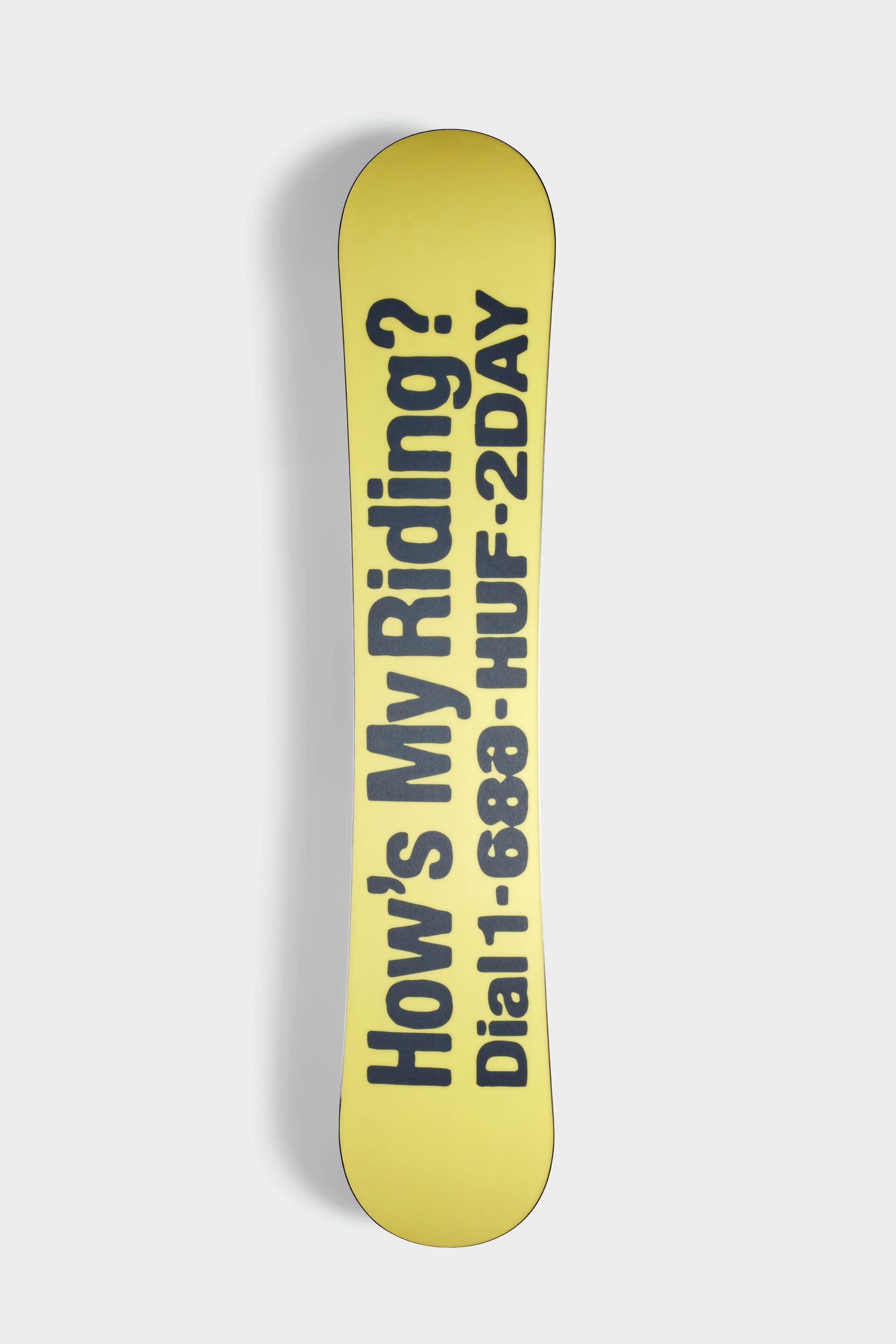 The 686 HUF Outerspace Living Snowboard by 686 features a yellow freestyle shape with bold black “How’s My Riding? Dial: 888-HUF-2DAY” text on the base, shown against a plain white background.