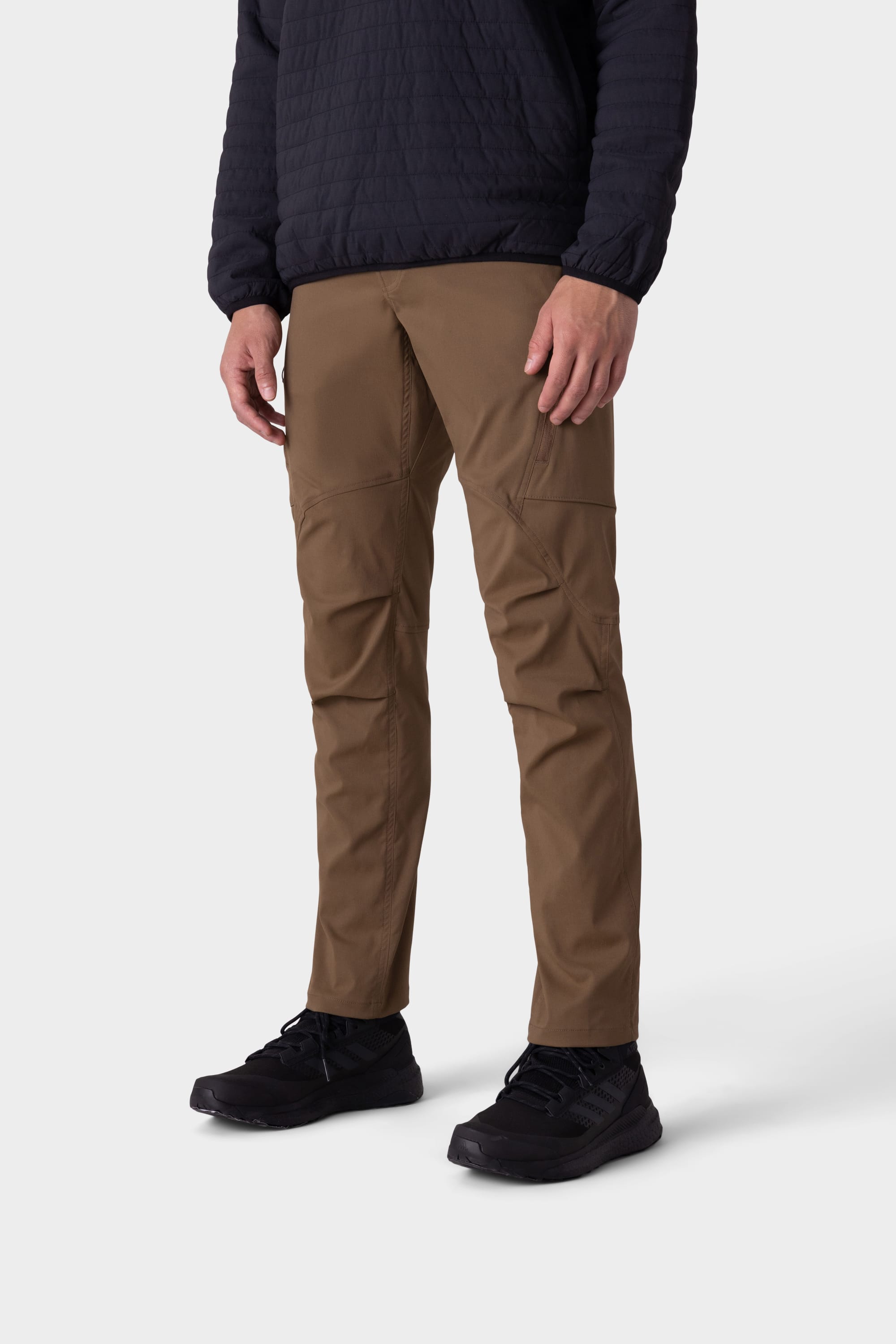 A person wearing a black quilted jacket, 686 Men’s Anything Cargo Pant - Slim Fit, and black sneakers stands against a plain white background.