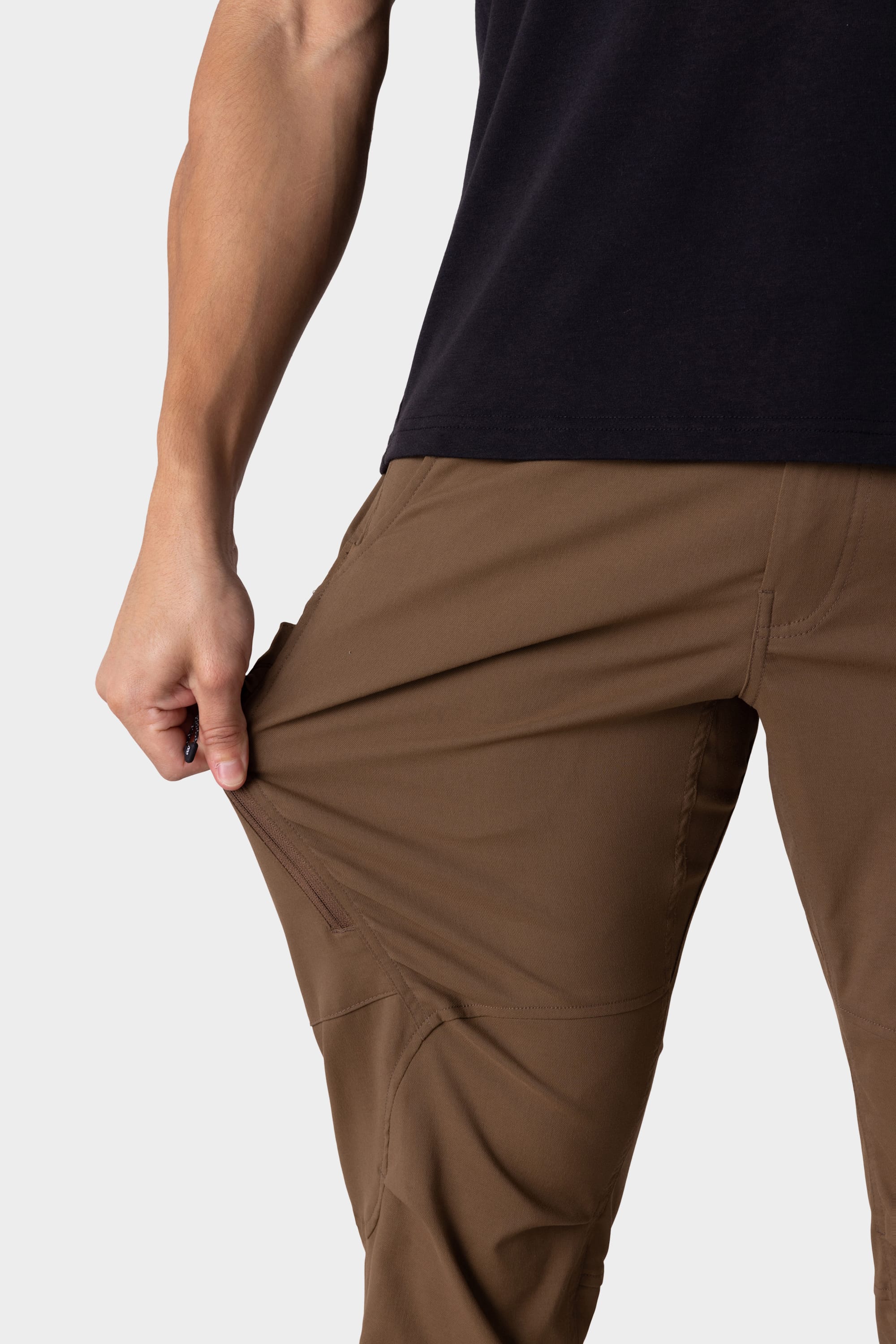 A person wearing 686 Mens Anything Cargo Pant - Slim Fit by 686 stretches the fabric outward, showcasing the flexibility and stretchiness of these versatile cargo pants.