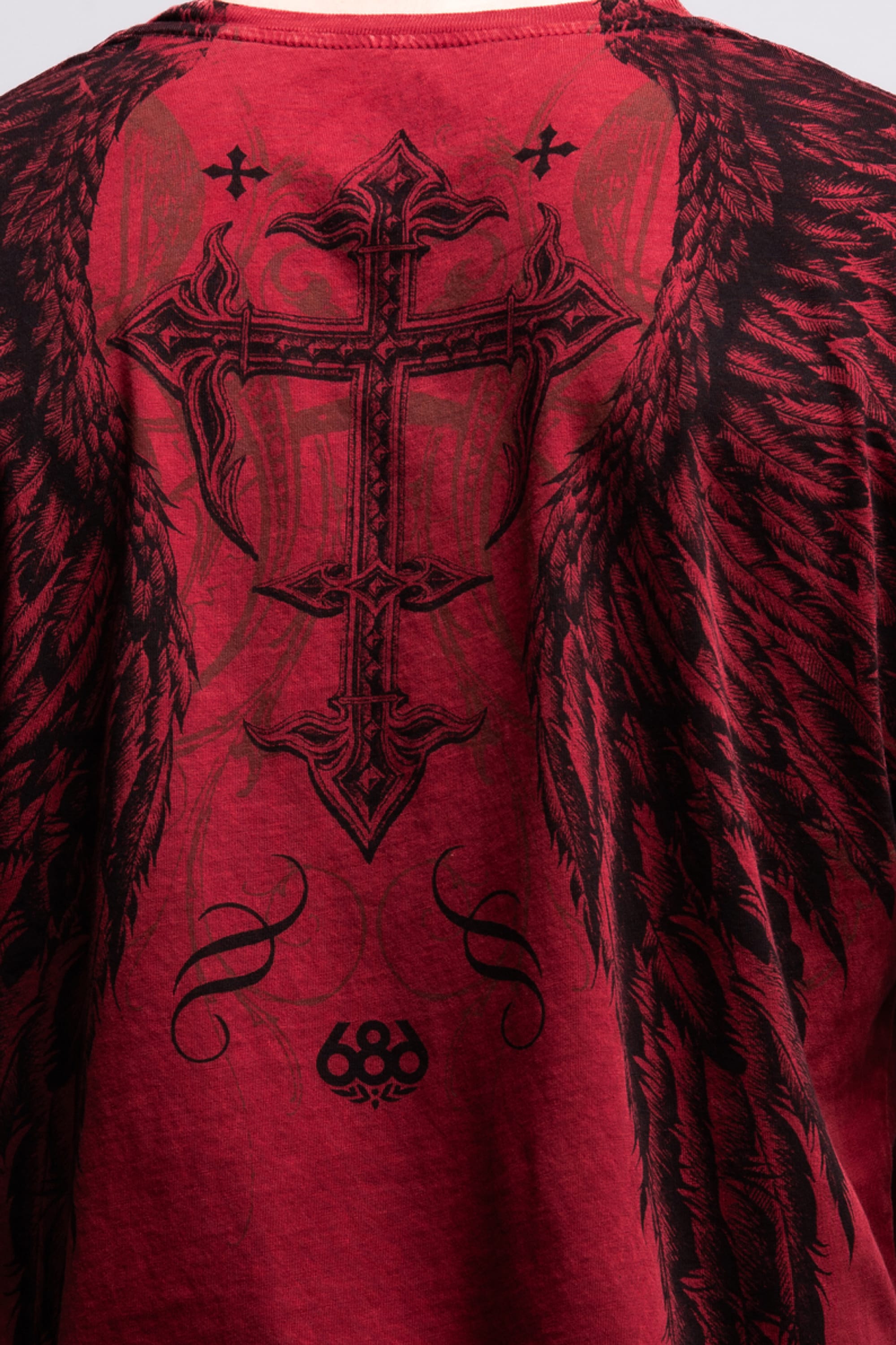 The 686 Affliction Death Eyes SS Tee by 686 is a bold red men‚Äôs t-shirt with a large black ornate cross, angel wings, swirling details, and the number 68 near the bottom. Made from 100% cotton for comfort and style.