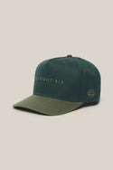 Introducing the 686 High-Pro Ses Two Tone Structured 5 Panel Hat by 686—a men's hat made from 100% cotton in a classic green color. It features "SIX EIGHT SIX" written in gold across the front and a small embroidered logo on the left side for stylish detail. Combining a timeless look with comfortable fit, this hat is perfect for everyday wear.
