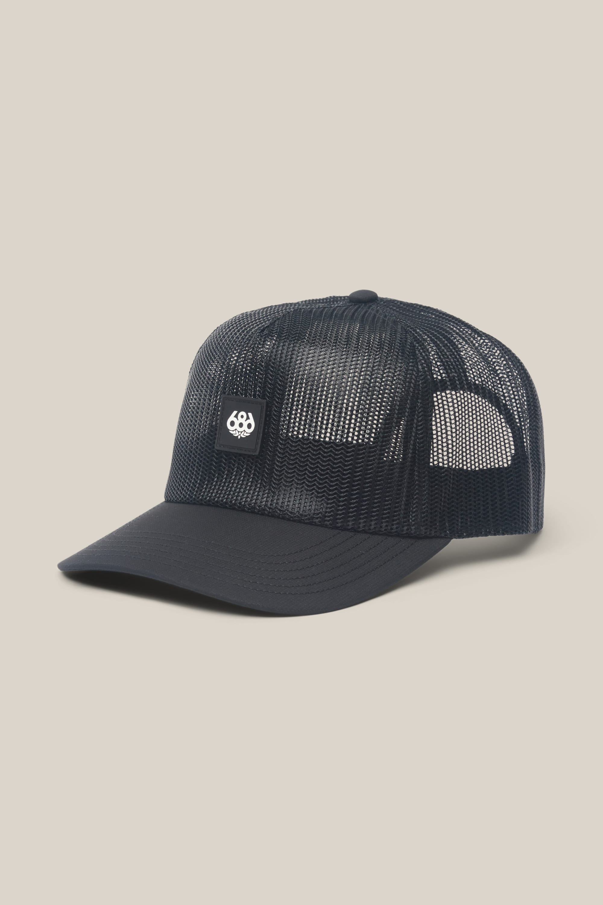 The 686 High-Pro Knockout Structured 5 Panel Hat by 686 is a black mesh men's cap with a curved brim and a small rectangular white logo patch on the front, shown against a light beige background.