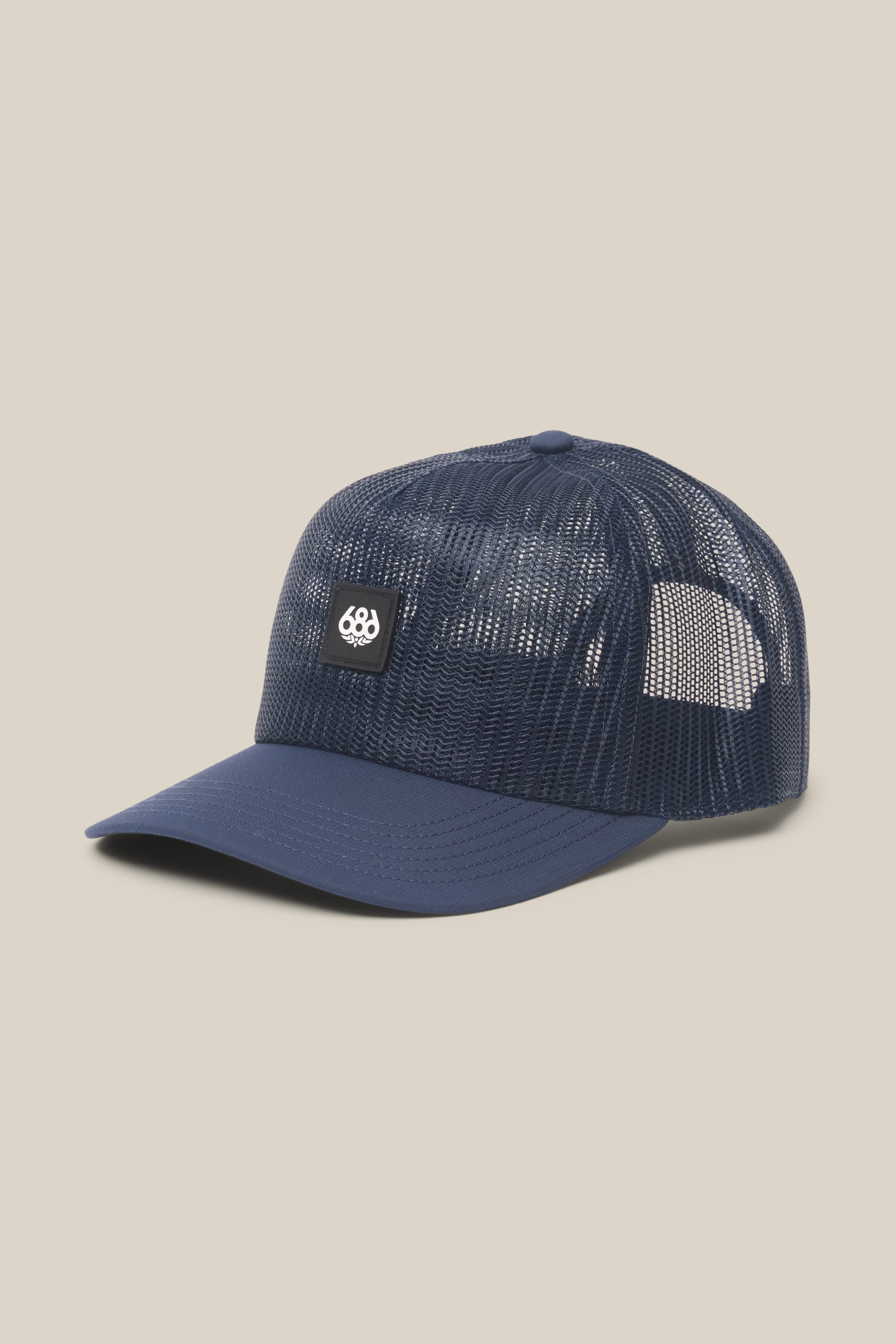 The 686 High-Pro Knockout Structured 5 Panel Hat by 686 is a navy blue men's mesh trucker hat with a curved brim and a small black patch featuring a white logo on the front, shown against a plain beige background.