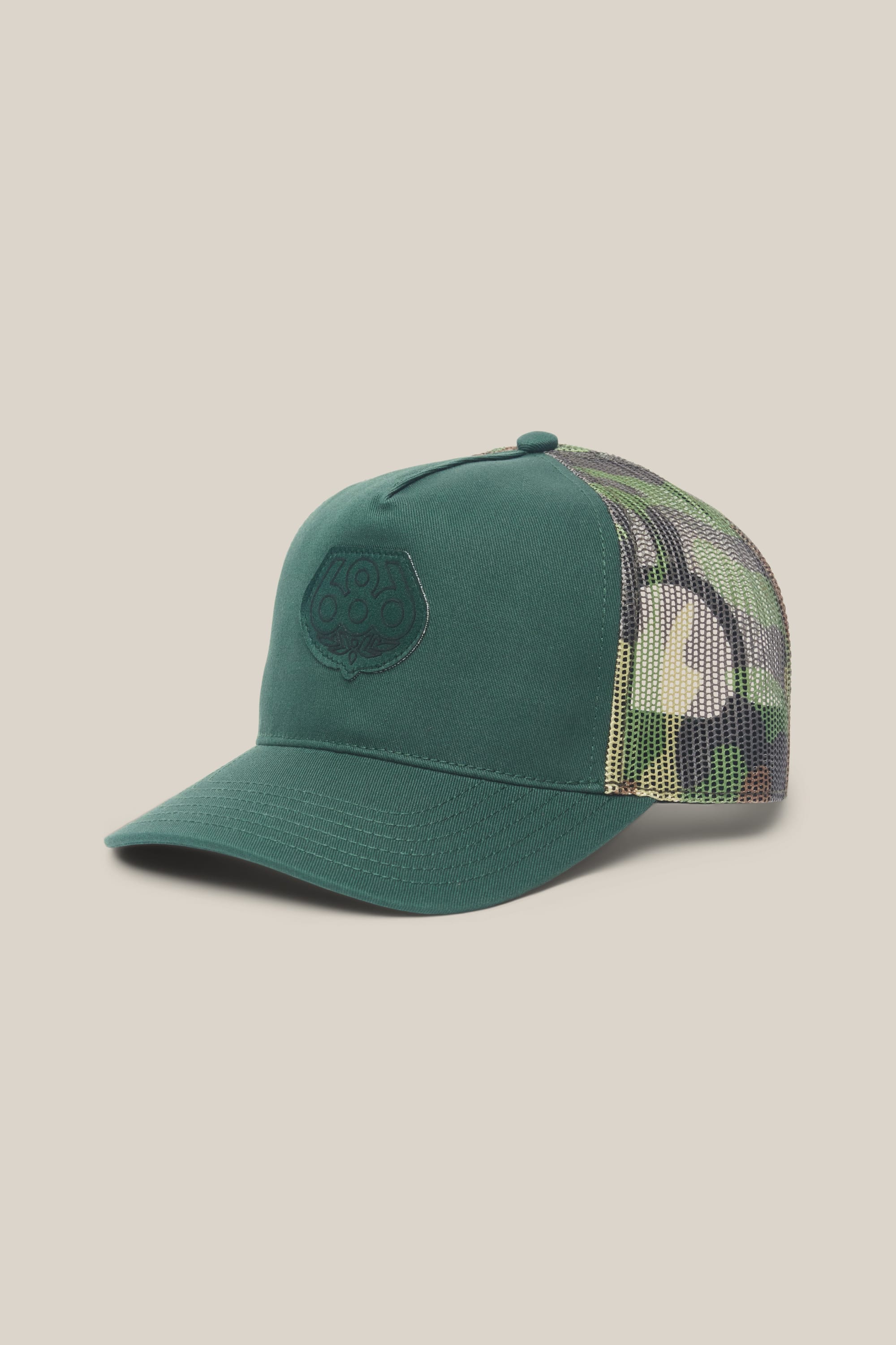 The 686 Mid-Pro Wreath Unstructured 5 Panel Mesh Hat by 686 is a green men's cap with a solid front panel featuring an embroidered logo and green camouflage mesh sides, displayed on a plain beige background.