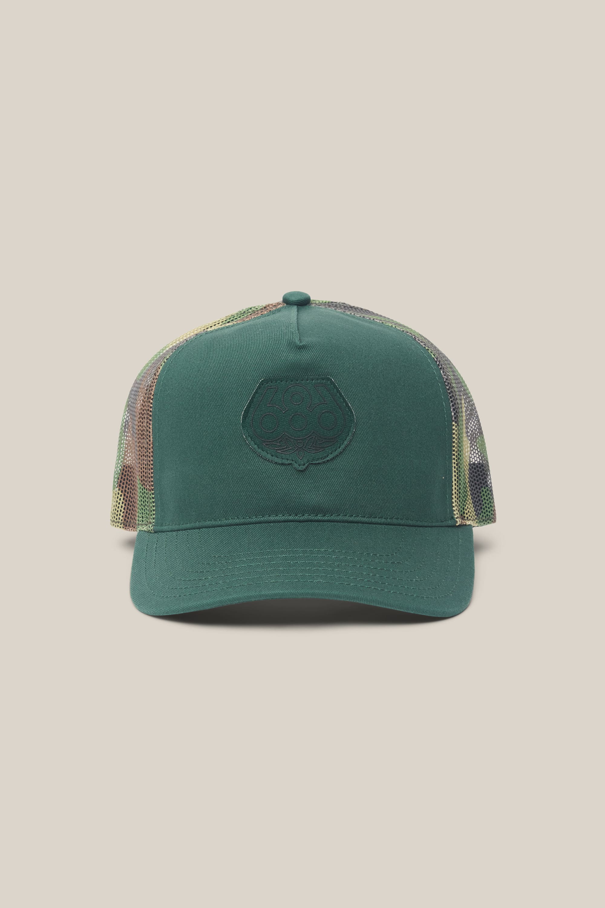 Introducing the 686 Mid-Pro Wreath Unstructured 5 Panel Mesh Hat by 686—a men's woven hat featuring a solid green front, mesh camouflage back, curved bill, and an embossed circular logo at the center. Crafted from a polyester-cotton blend, this hat is displayed against a light beige background.