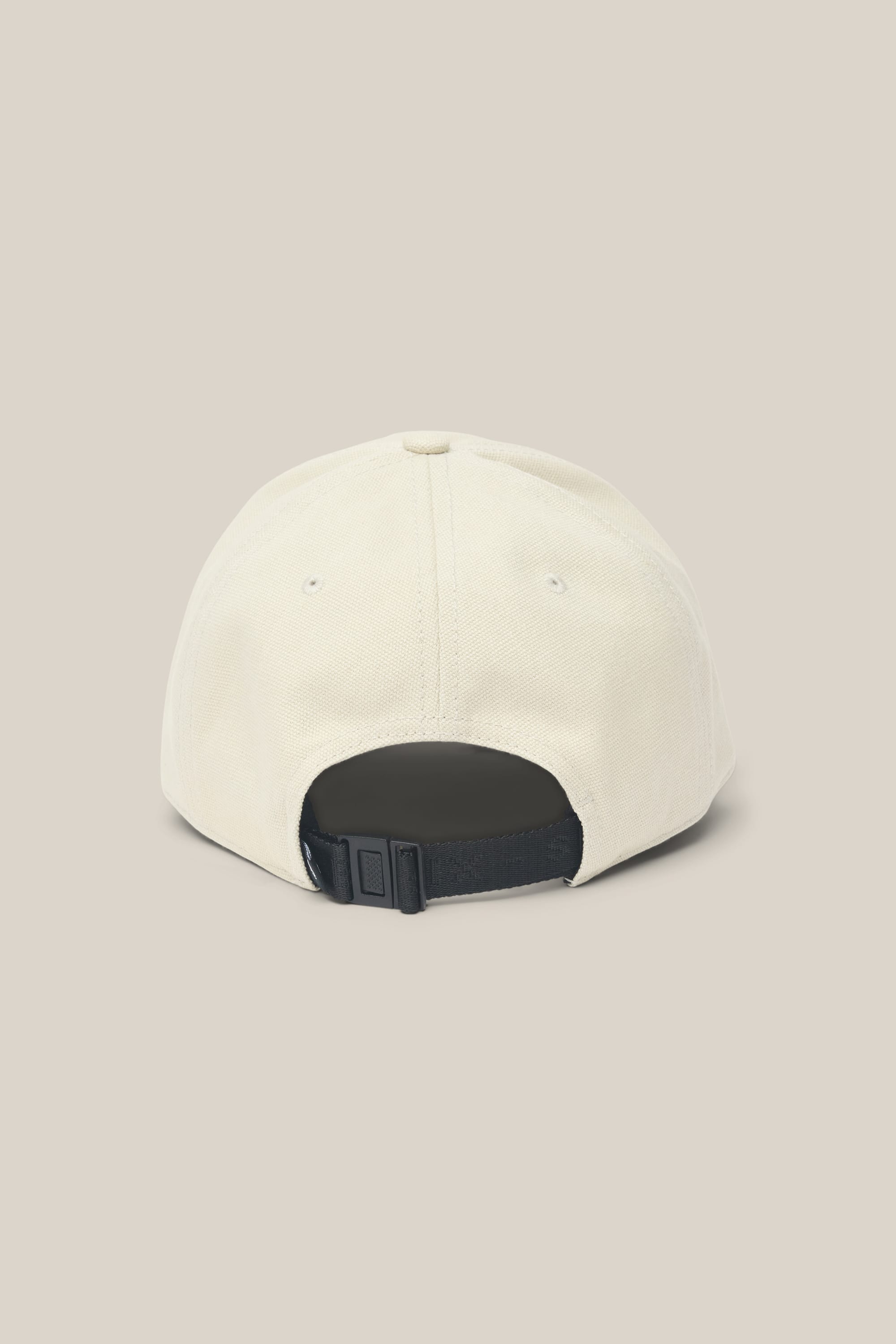 The 686 Low-Pro Unwork Unstructured 6 Panel Hat by 686 is a beige men's polyester hat, shown from the back with a black adjustable strap and buckle, set against a light beige background.
