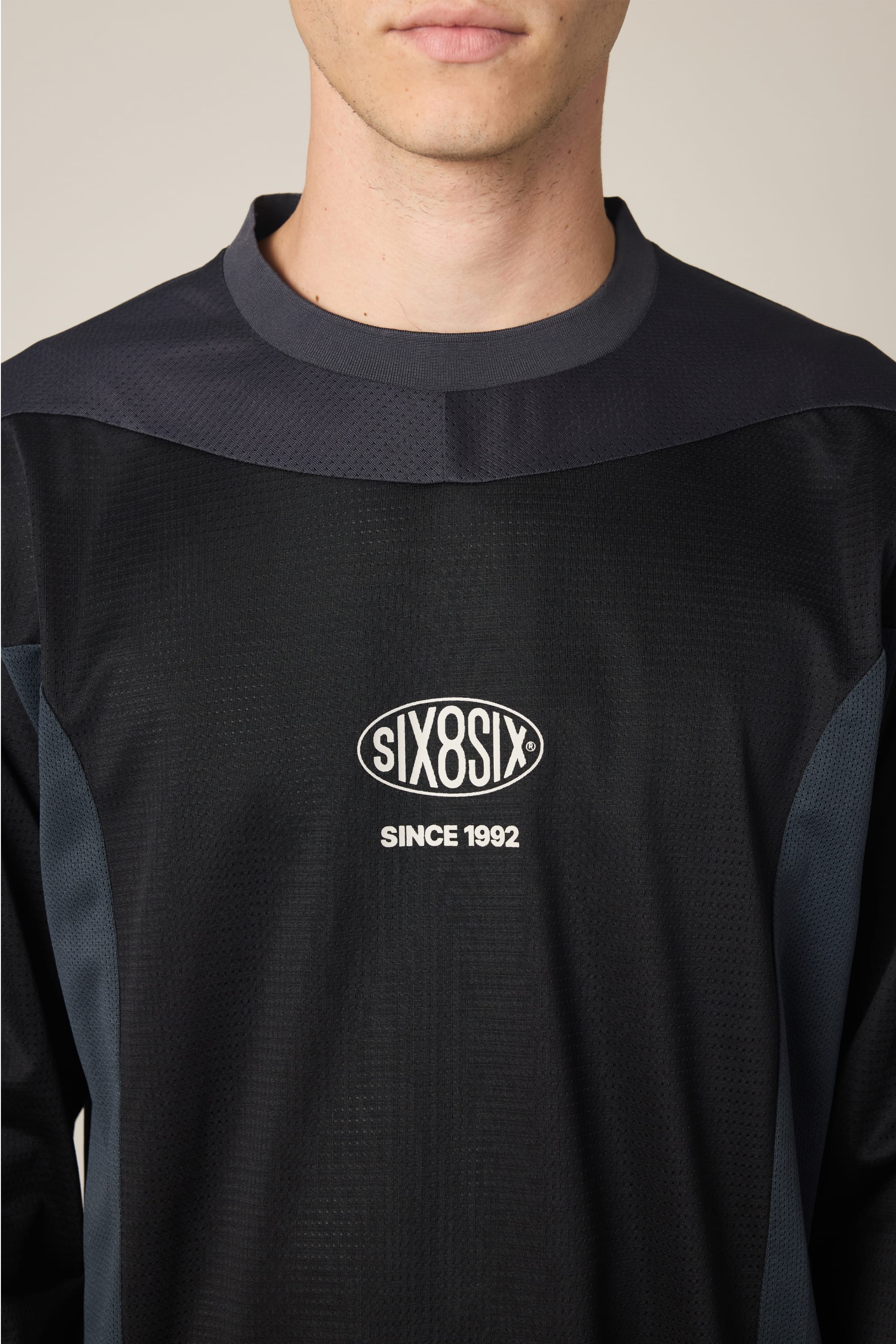 A man wears the 686 Men's 92 Turbo LS Tech Tee—a black polyester shirt with dark gray accents and "SIX8SIX SINCE 1992" on the front. Styled casually, only his lower face is visible. Brand: 686.