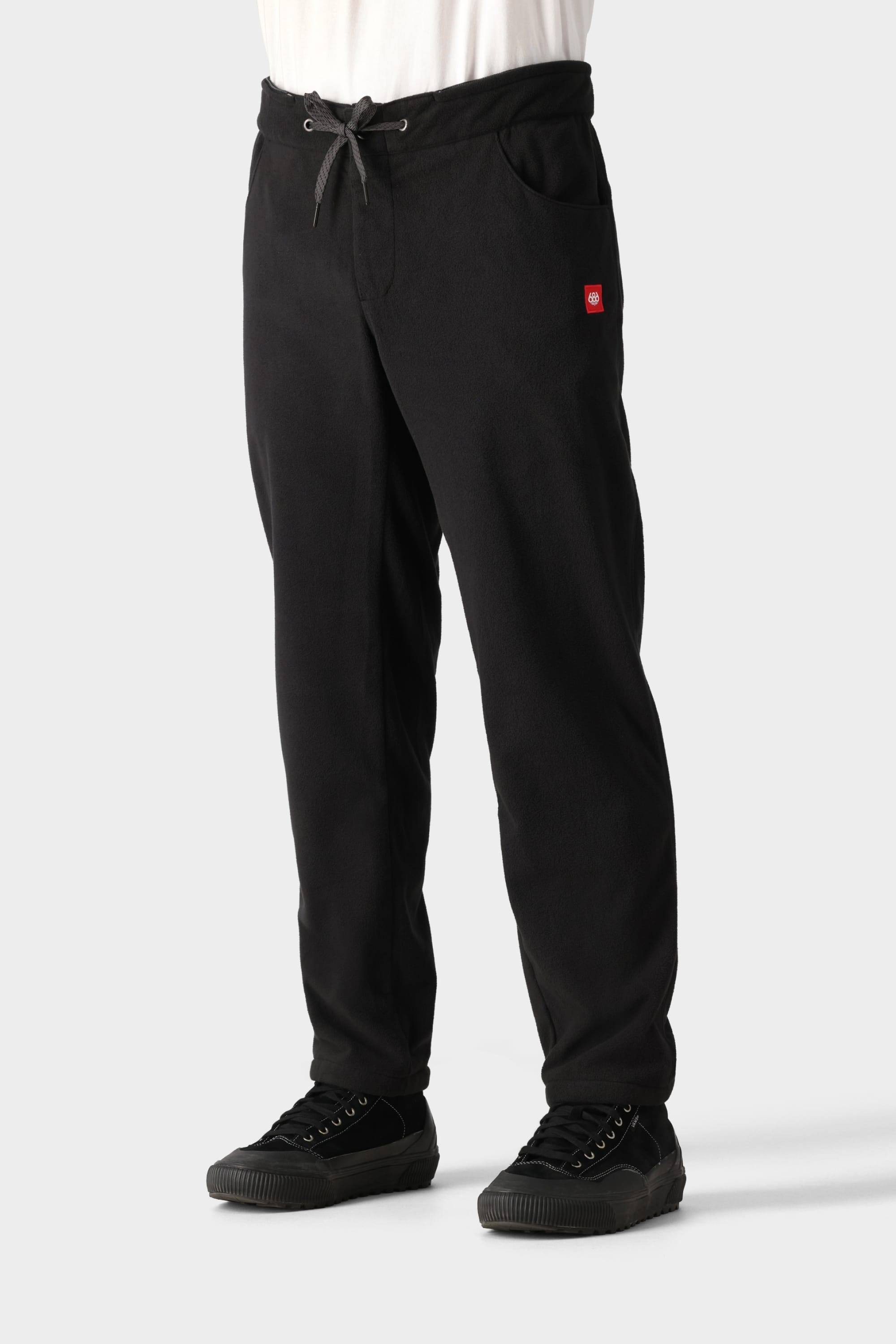 A person wearing 686 Men’s SMARTY® 3-in-1 Cargo Pants by 686, paired with a white shirt and black sneakers, stands against a plain light gray background.