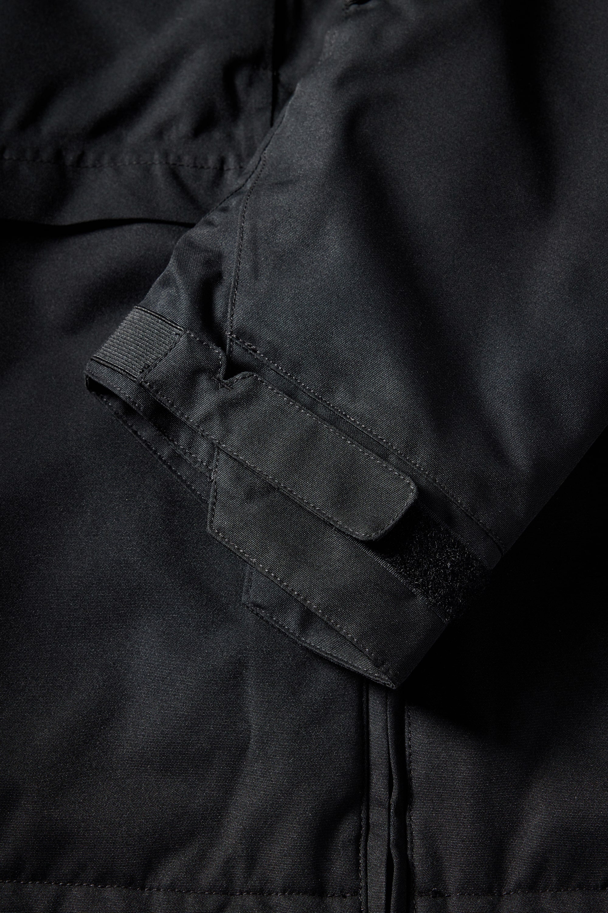 Close-up of the 686 Mens Geo Insulated Jacket sleeve shows a Velcro strap and visible stitching on smooth, matte fabric, highlighting the jackets subtle tech features.