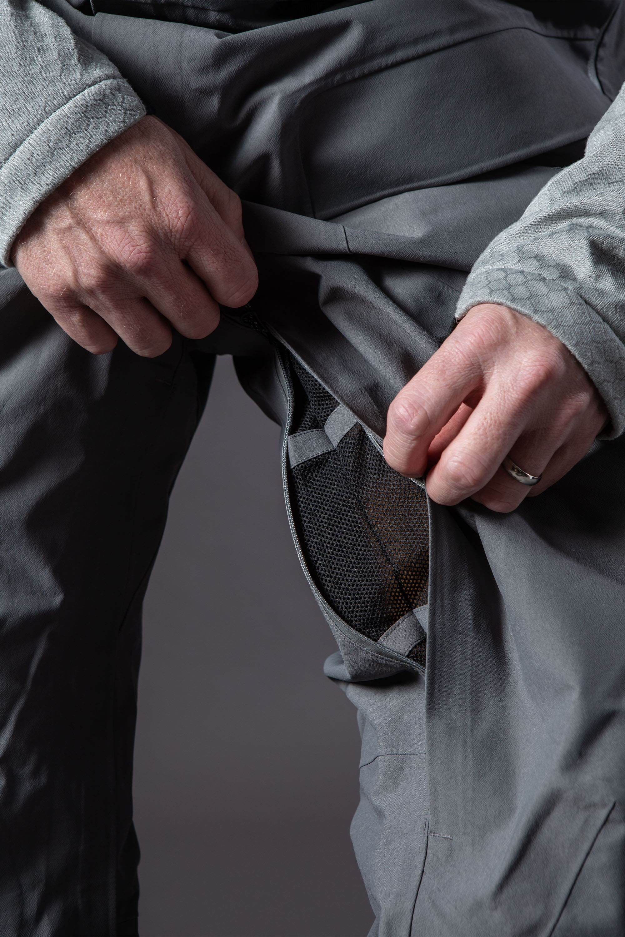 A person wearing the 686 Mens GORE-TEX PRO 3L Thermagraph Bib unzips a mesh-vented thigh opening, demonstrating the ventilation feature of these pants from 686.