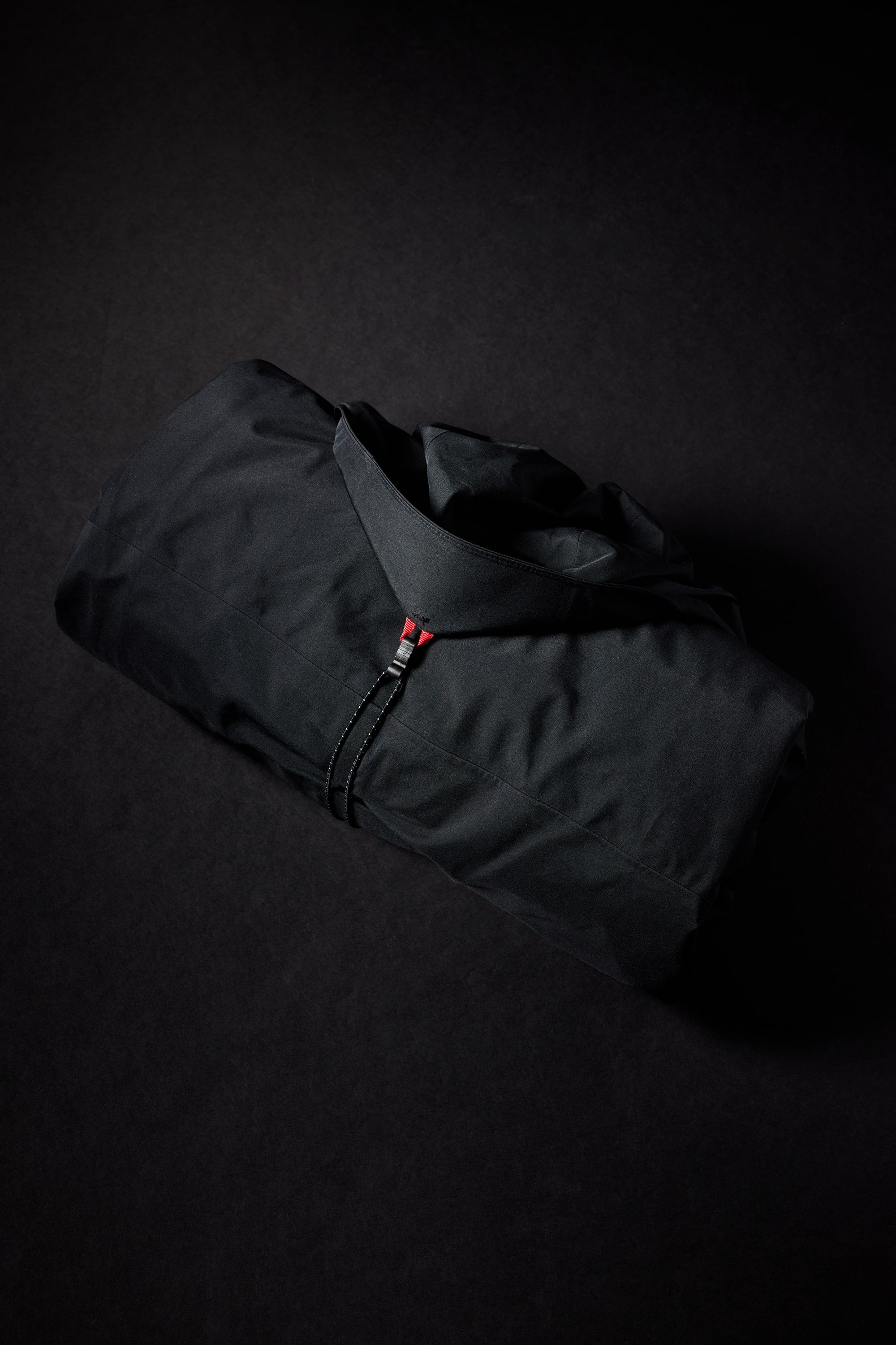 The 686 Womens Hydra Insulated Jacket by 686, a black waterproof coat with a collar, light insulation, and a visible zipper, is neatly folded on a dark background.