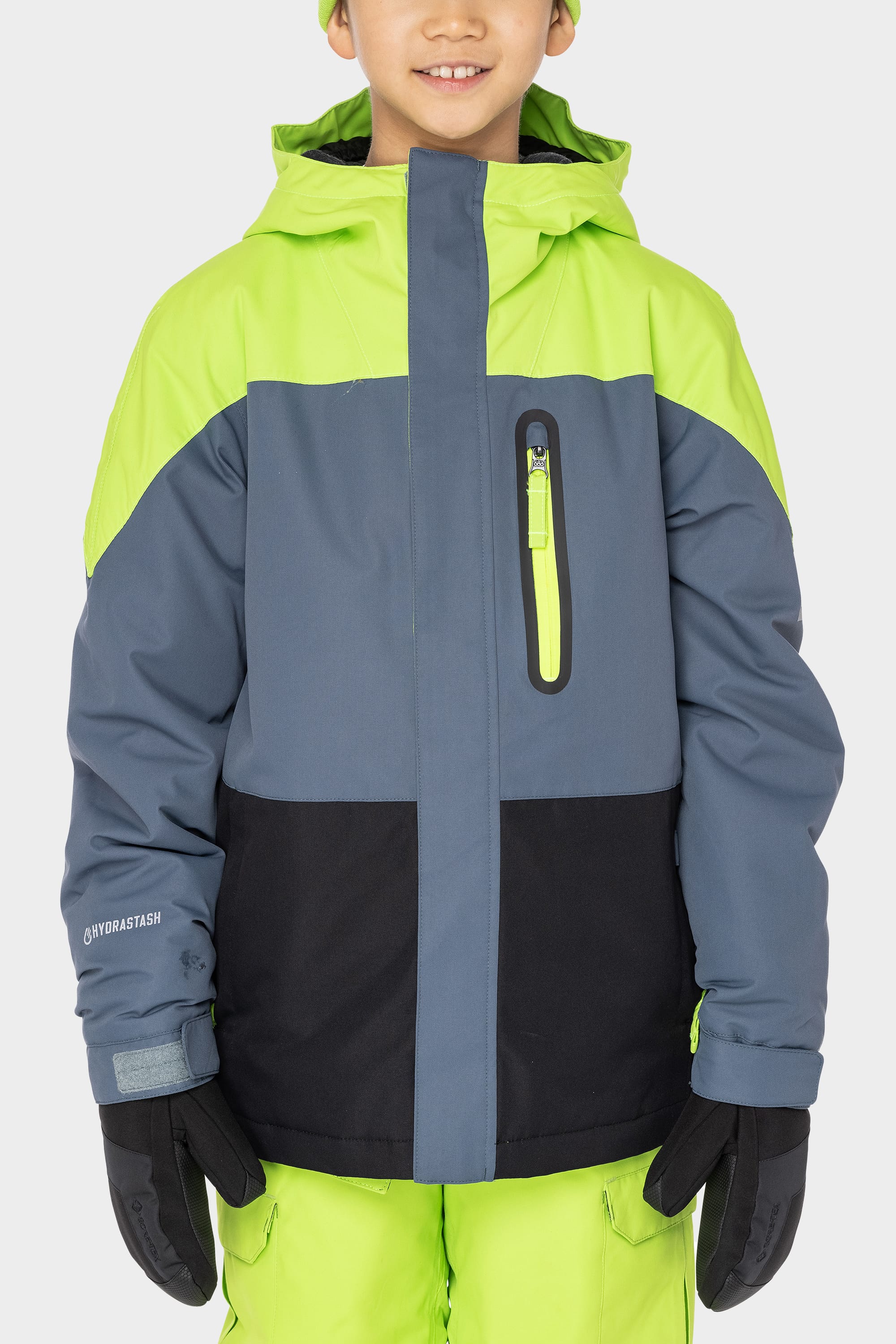 A child wearing the 686 Boys Hydrastash Insulated Jacket in neon green, gray, and black from 686, paired with matching neon green snow pants and black gloves, stands against a plain white background.