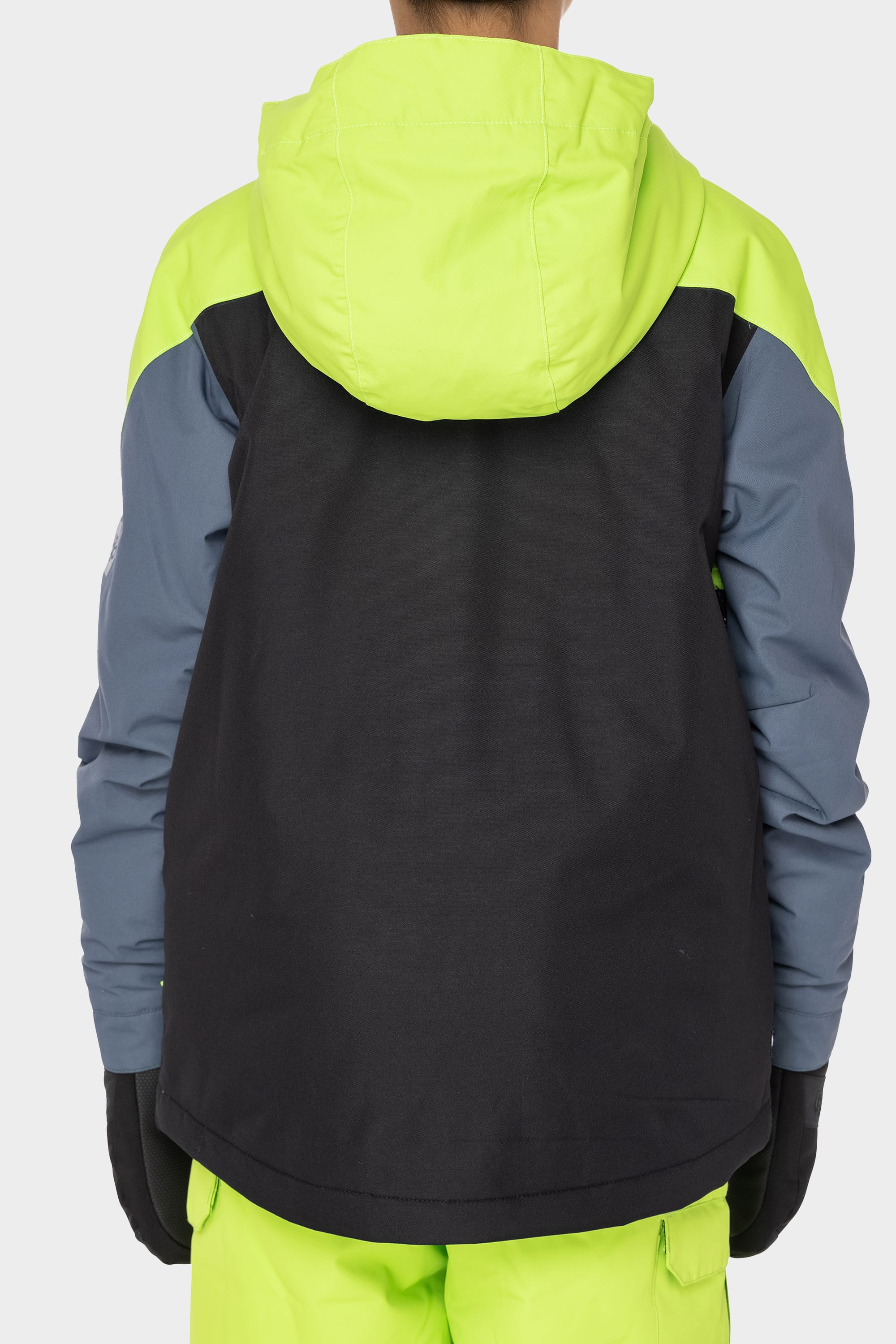 A person is seen from the back wearing the 686 Boys Hydrastash Insulated Jacket in neon yellow, black, and gray, paired with matching neon yellow pants and black gloves.