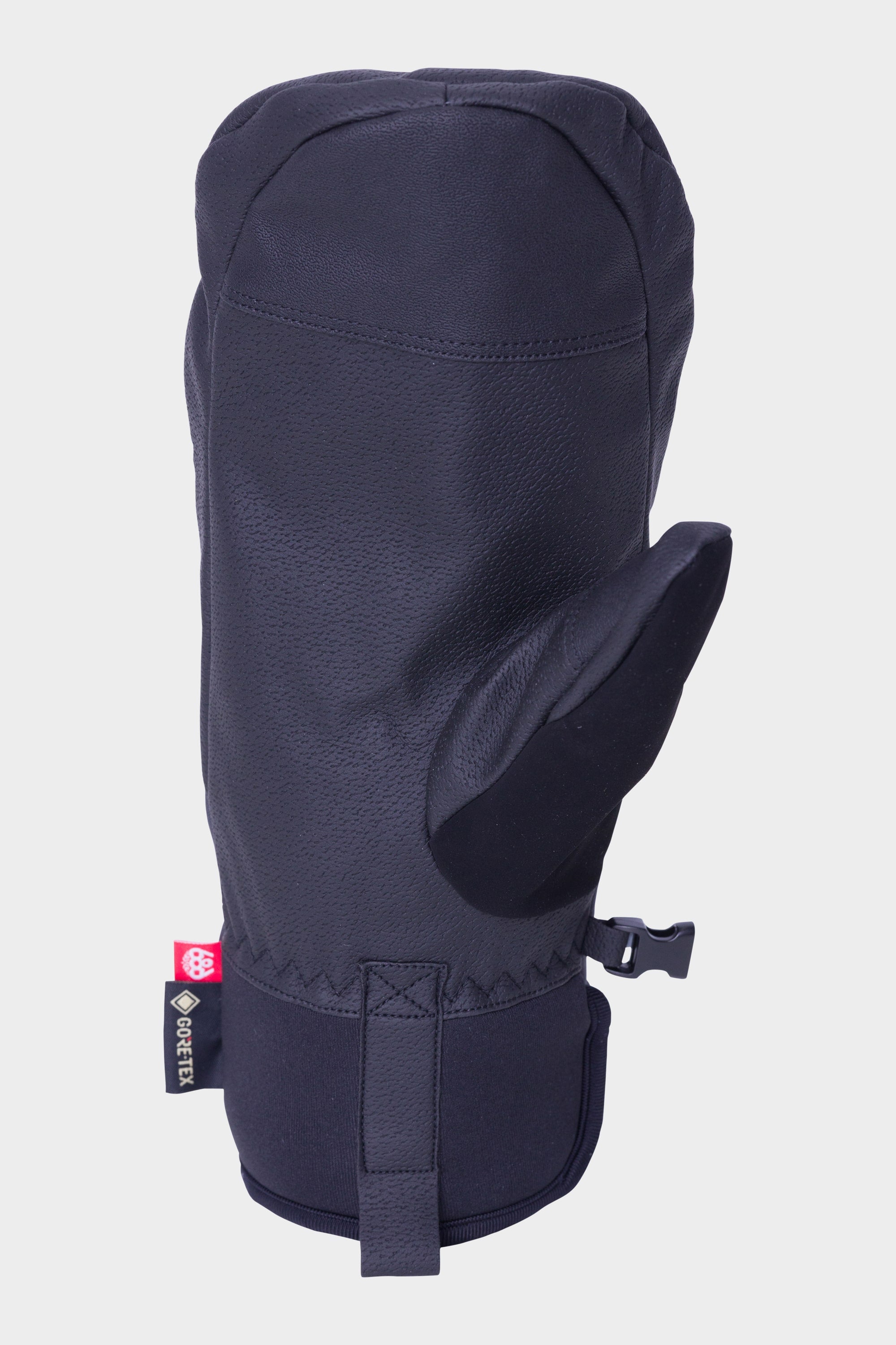 The 686 Mens GORE-TEX Linear Under Cuff Mitt by 686 is a black mitt with a textured surface, thumb section, wrist strap, and a small GORE-TEX label on the side, shown against a plain light background for superior waterproofing.