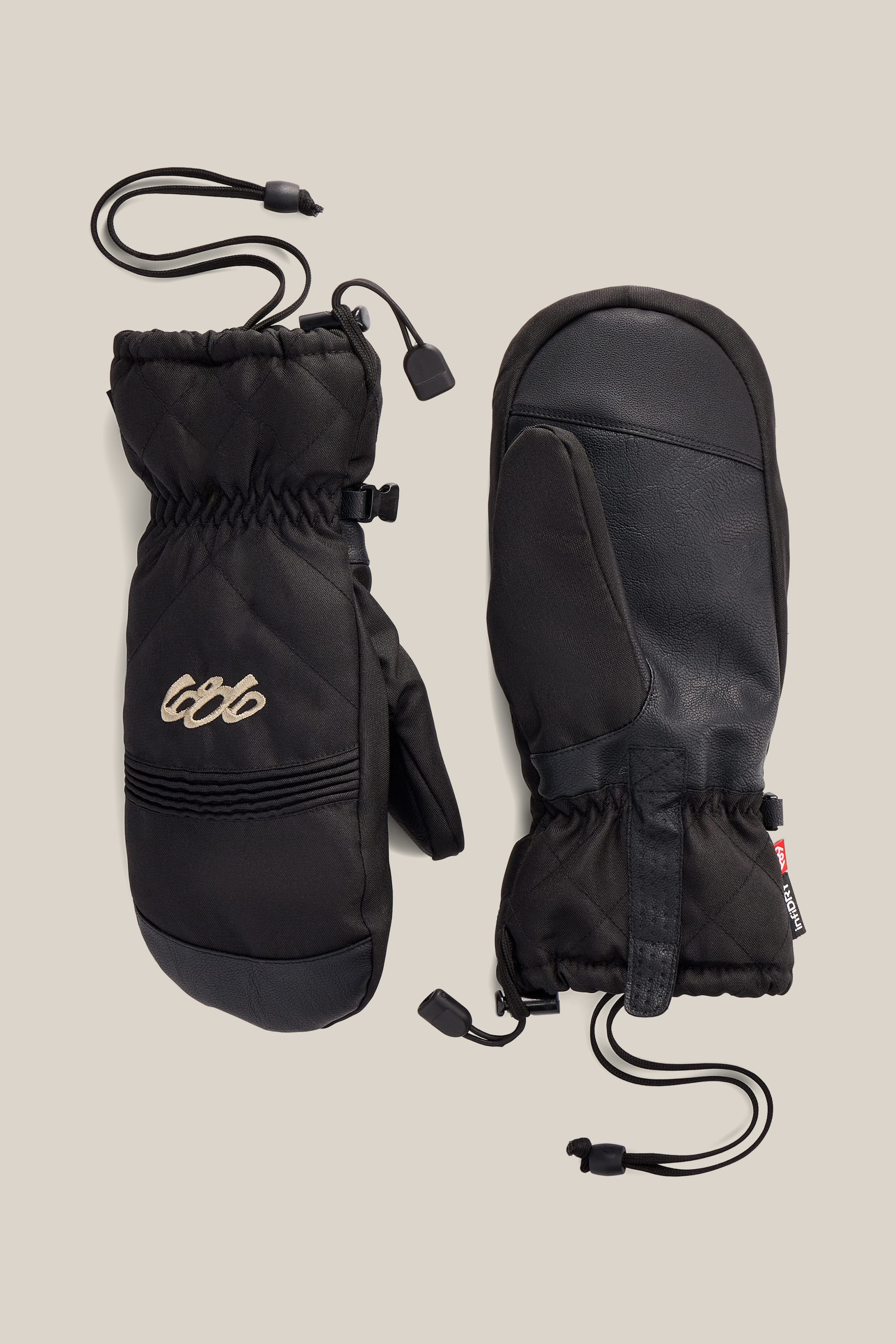 Two 686 Women’s Jubilee™ Mitts in black are displayed on a neutral background, showing both the palm and back sides. One mitten features stitched detailing and a small embroidered 686 logo, with drawstring cords for insulation.