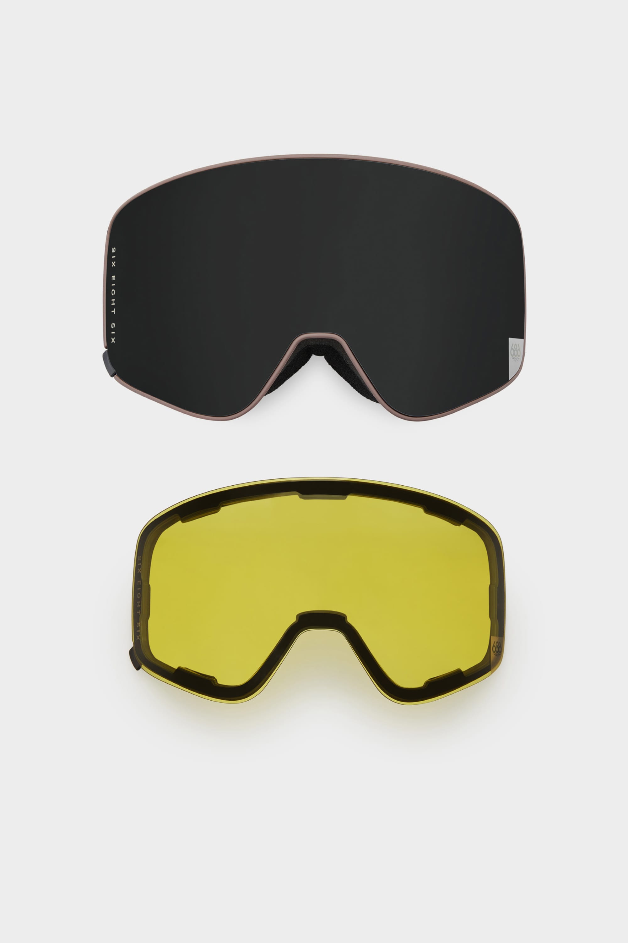 The 686 SMARTY Goggle by 686 features two interchangeable magnetic lenses, one dark and one yellow, suitable for all conditions. Both minimalist lenses are displayed on a plain white background.