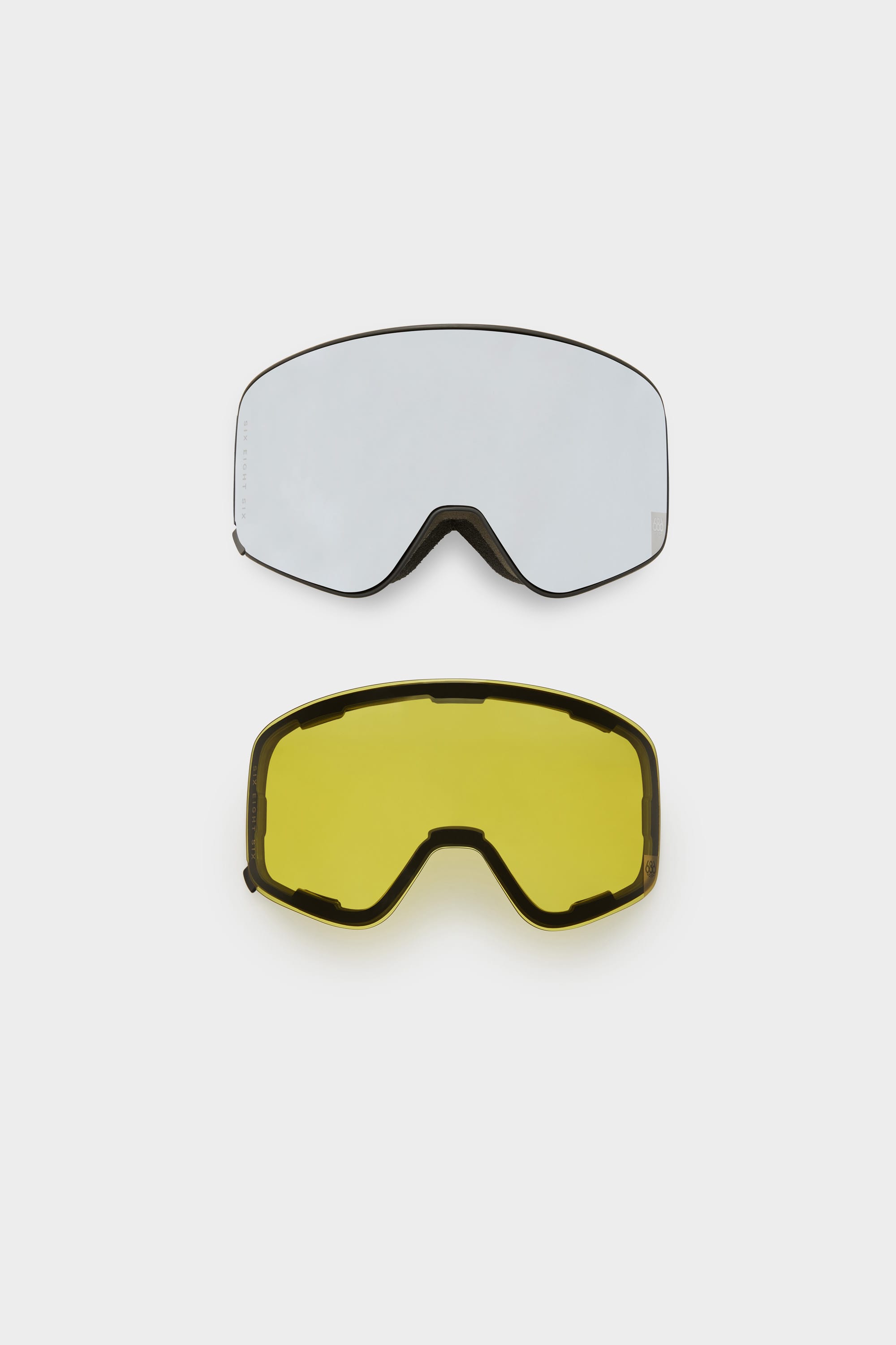 Two interchangeable 686 SMARTY Goggle lenses by 686 are shown on a white background: the top is clear, the bottom is yellow—providing versatile options for any weather conditions.