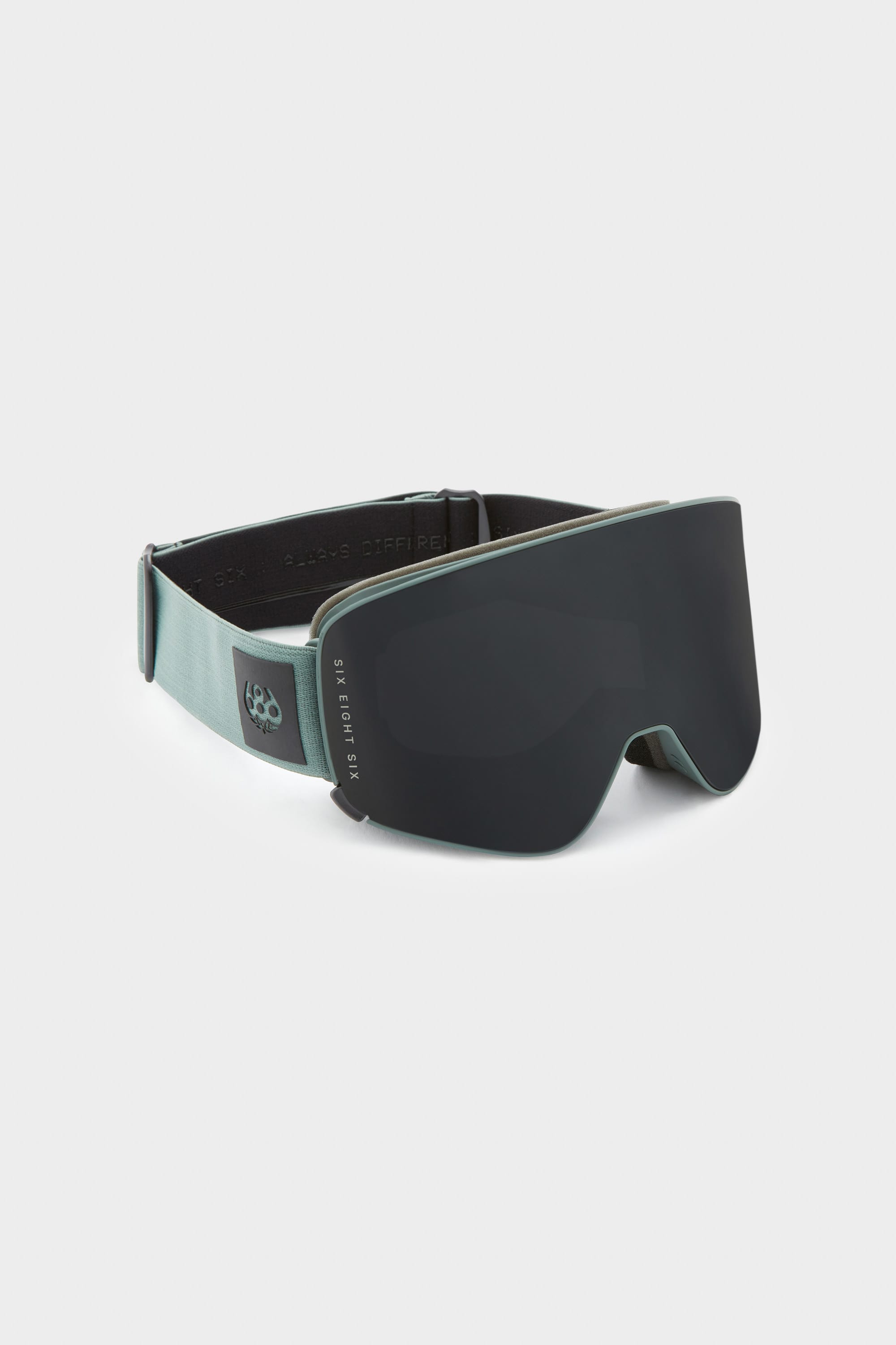 The 686 SMARTY Goggle by 686 features a modern minimalist design with a wide, dark-tinted magnetic lens and light gray adjustable strap, suitable for all conditions and shown on a plain white background.