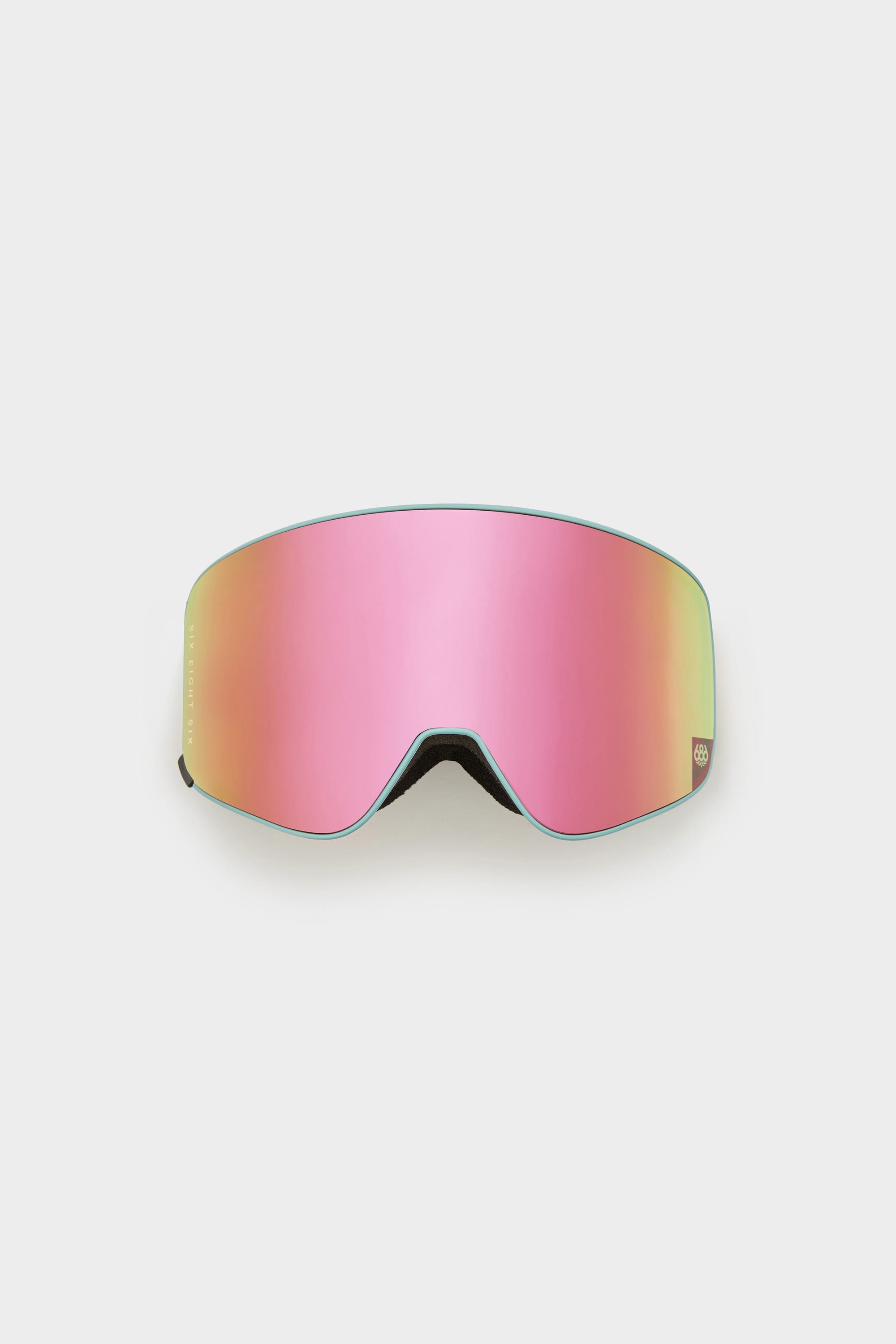 The 686 SMARTY Goggle by 686 features a frameless, minimalist design with a large curved pink lens reflecting green and yellow hues. Magnetic lenses allow easy swaps for any condition, all set against a plain light background.