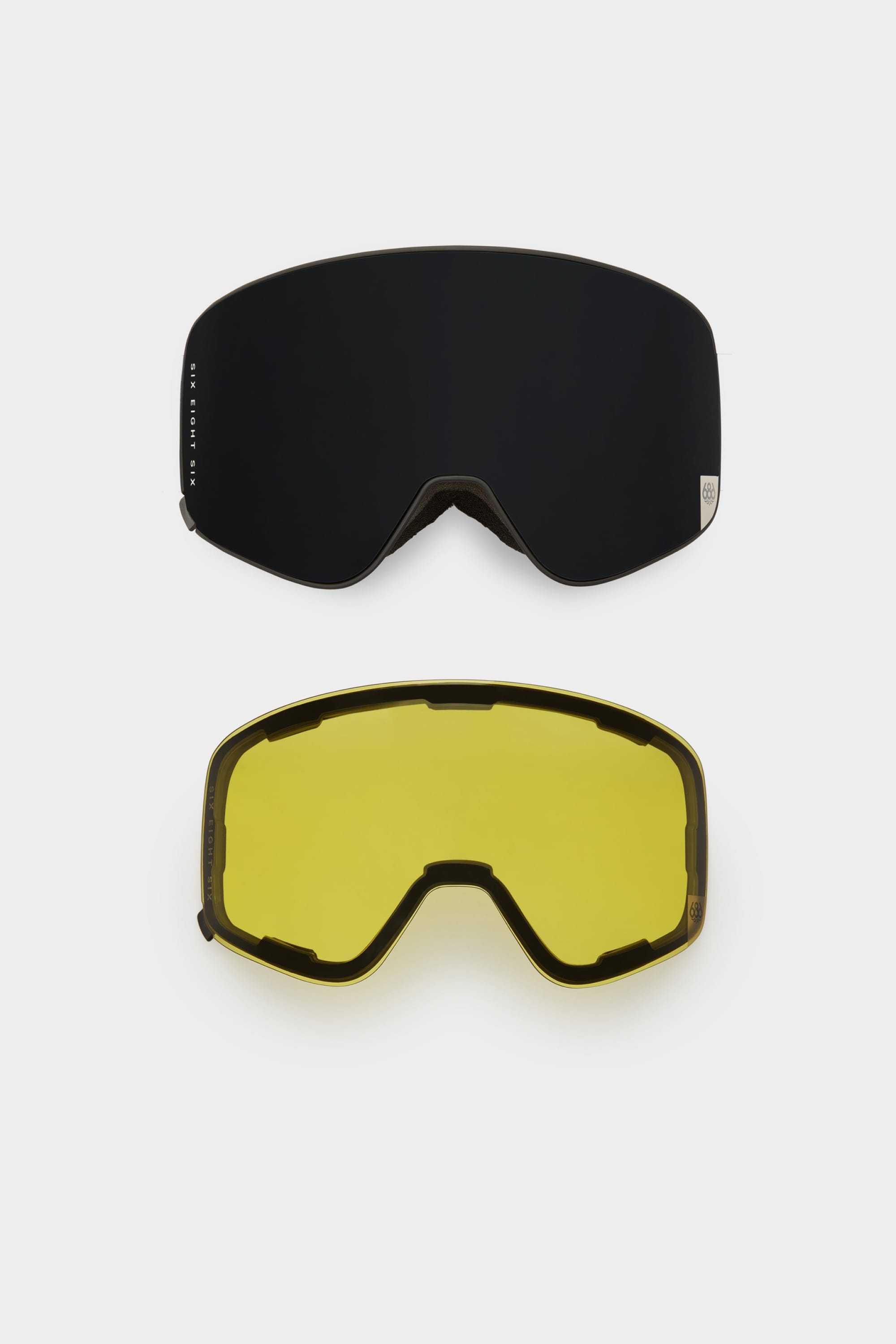 The 686 SMARTY Goggle by 686 is shown with two interchangeable magnetic lenses—one dark, one yellow—both wide and curved for versatile use, displayed on a white background.
