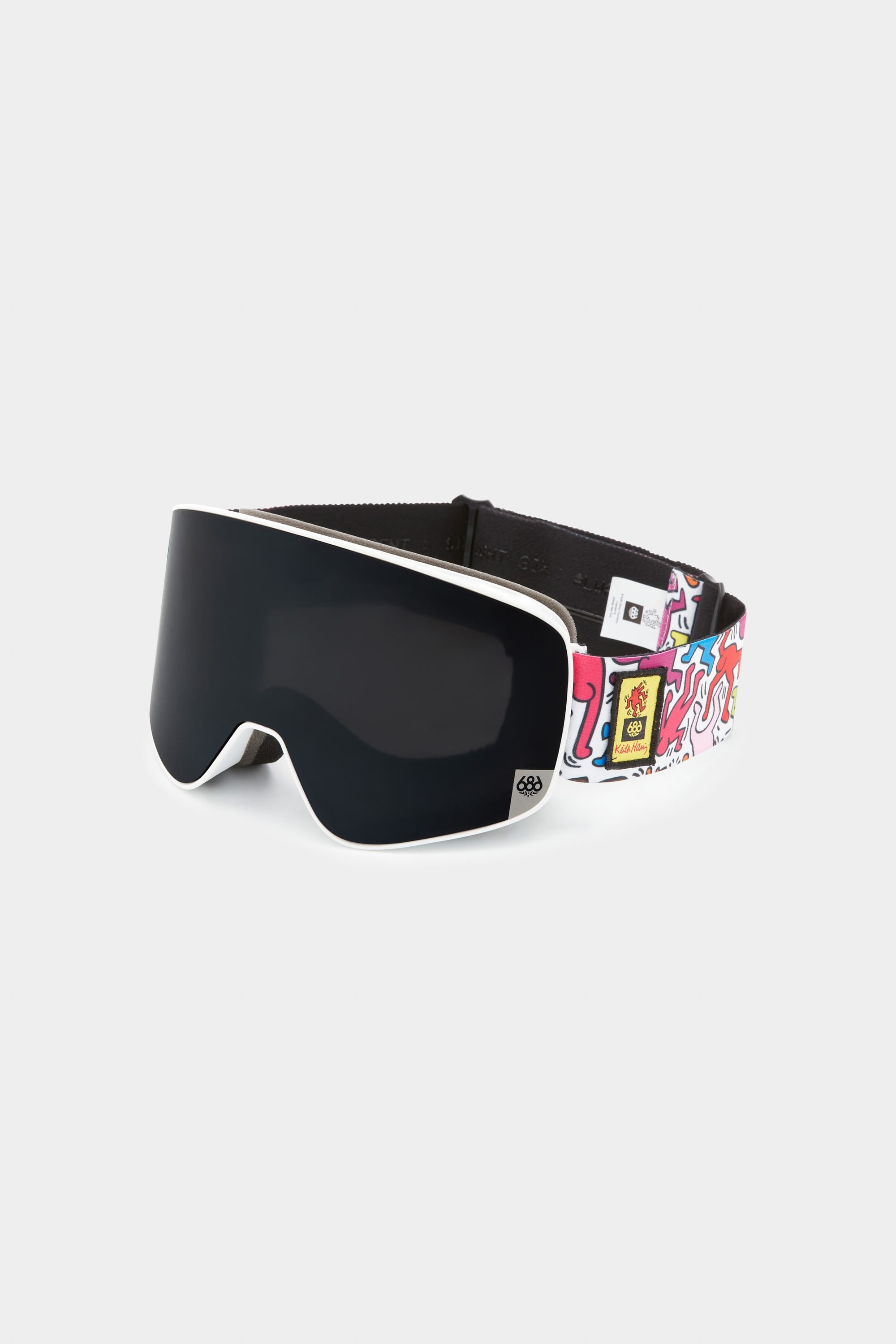 The 686 SMARTY Goggle by 686 features a black lens, white trim, and a vibrant graffiti-style strap with unique illustrations. Magnetic lenses allow fast swaps for any condition, blending minimalist design with standout style.