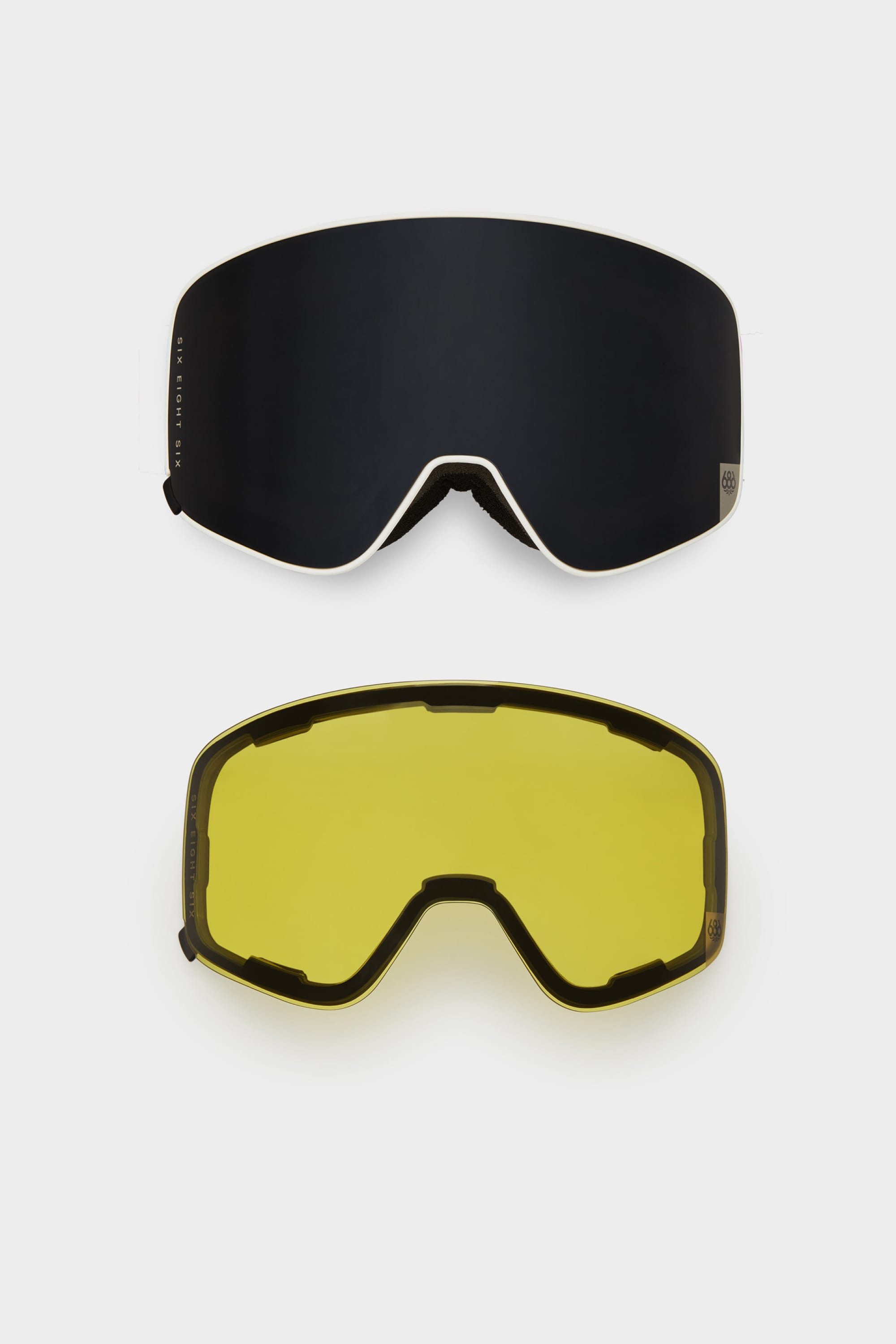 Two interchangeable 686 SMARTY Goggle lenses from 686—one dark mirrored, one yellow-tinted—are shown on a white background. Both have a frameless, curved design and magnetic lenses for fast swaps in any conditions.