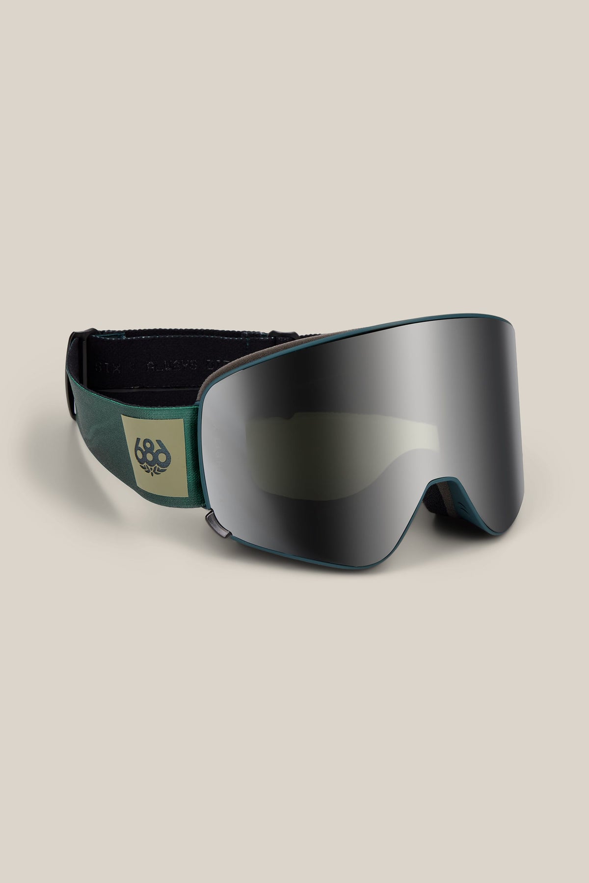 The 686 SMARTY® Magnetic Goggle by 686, featuring a dark, reflective lens and a green and black strap with a yellow 686 logo, is displayed against a plain beige background.