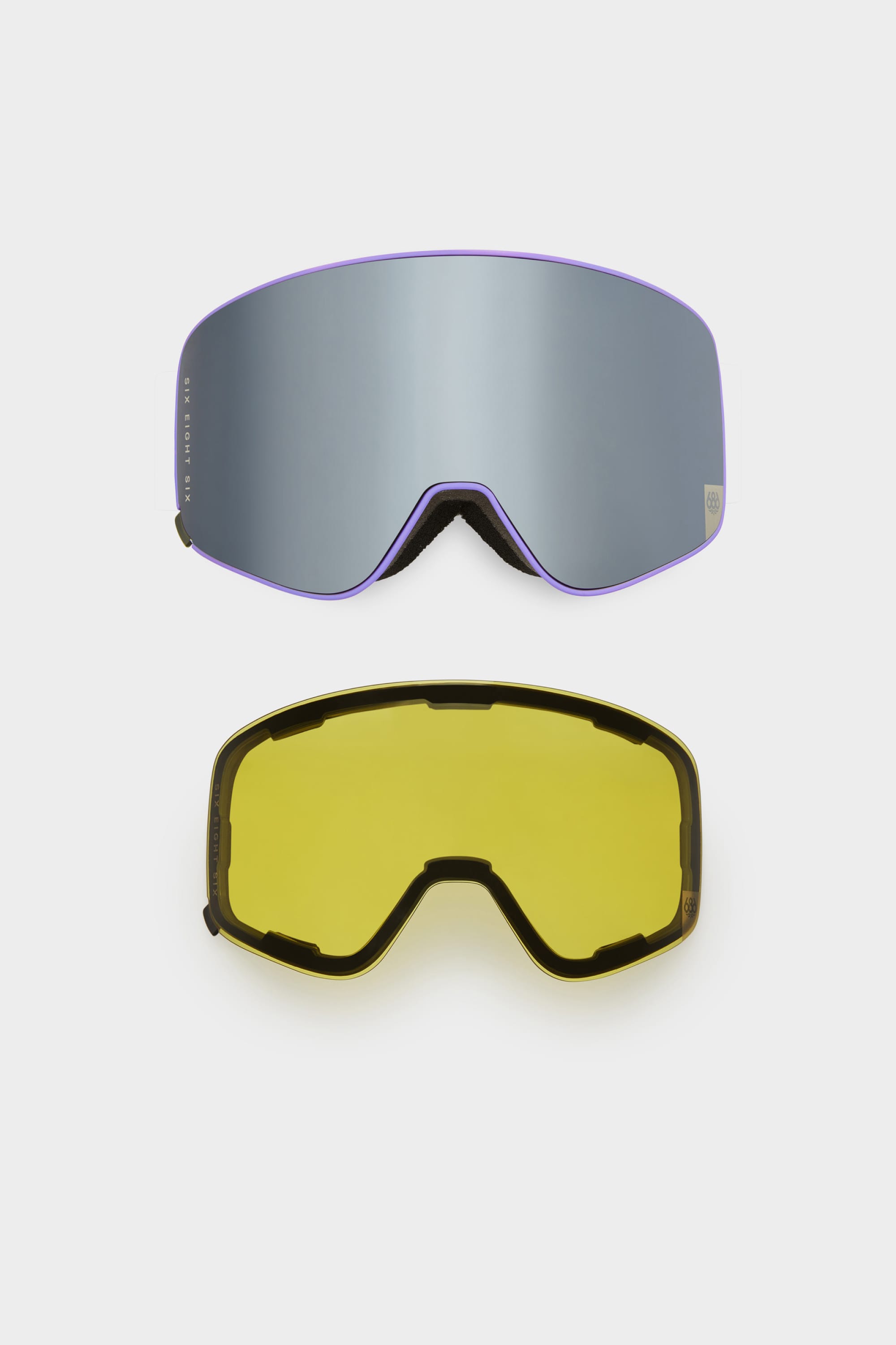 Two interchangeable magnetic lenses for the 686 SMARTY Goggle by 686 are shown on a white background: the top lens is reflective with a purple tint, and the bottom lens is yellow with a black frame outline.