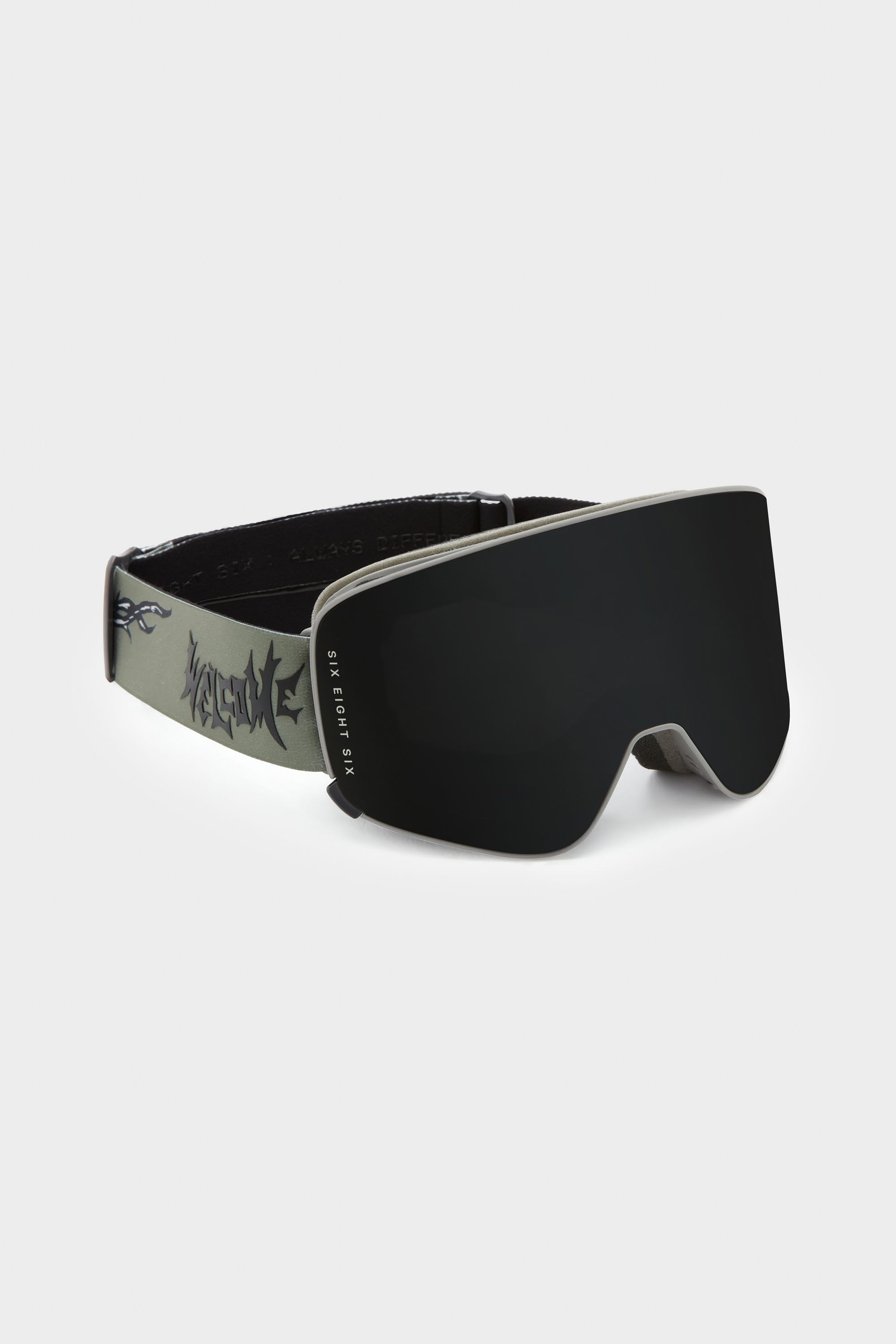 The 686 SMARTY Goggle by 686 features a modern, minimalist look with a seamless black lens and wide gray strap with bold black graphics. Magnetic lenses allow fast swaps for any conditions. Shown on a plain light background.