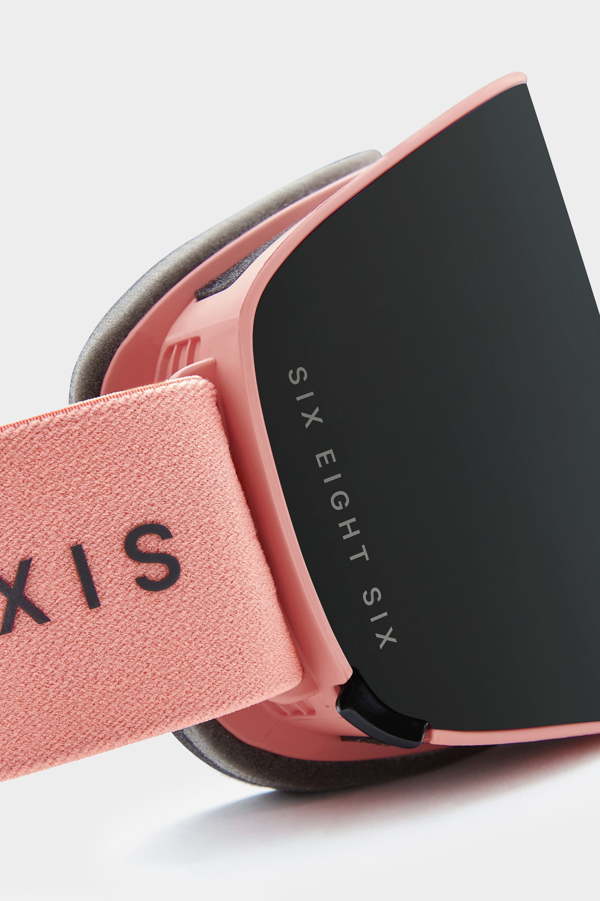 Close-up of the 686 SMARTY Goggle, a pink minimalist design with black magnetic lenses. The strap features black text and SIX EIGHT SIX in white on the lens side. Inside, foam padding ensures comfort for all conditions. Brand: 686.