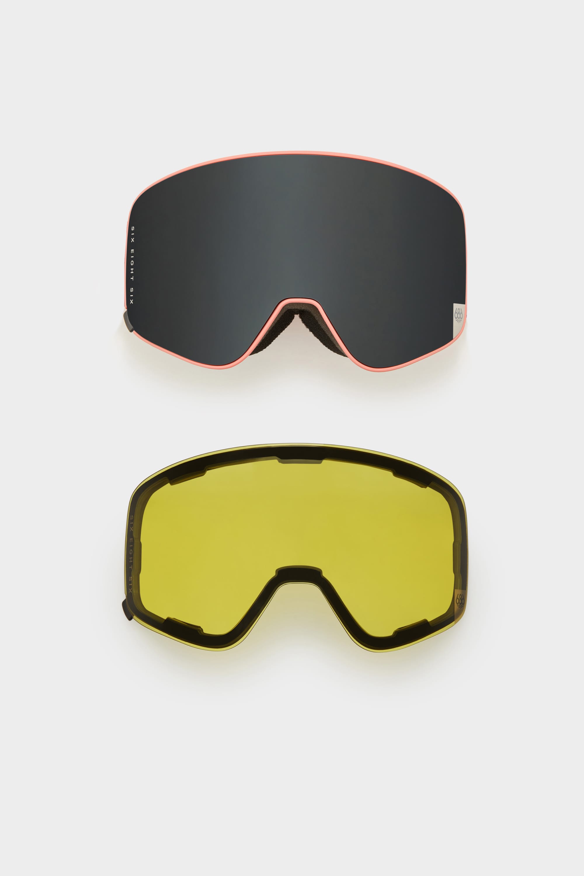 The 686 SMARTY Goggle by 686, featuring minimalist black lenses with red trim and an interchangeable yellow lens, uses magnetic technology for easy swaps. Both lenses are shown against a plain white background.