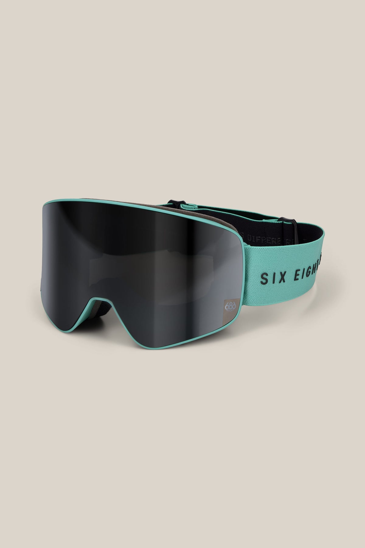 The 686 SMARTY® Magnetic Goggle by 686 is shown in matte black with a teal frame and an elastic teal strap featuring the text SIX EIGHT in black, displayed on a plain beige background.
