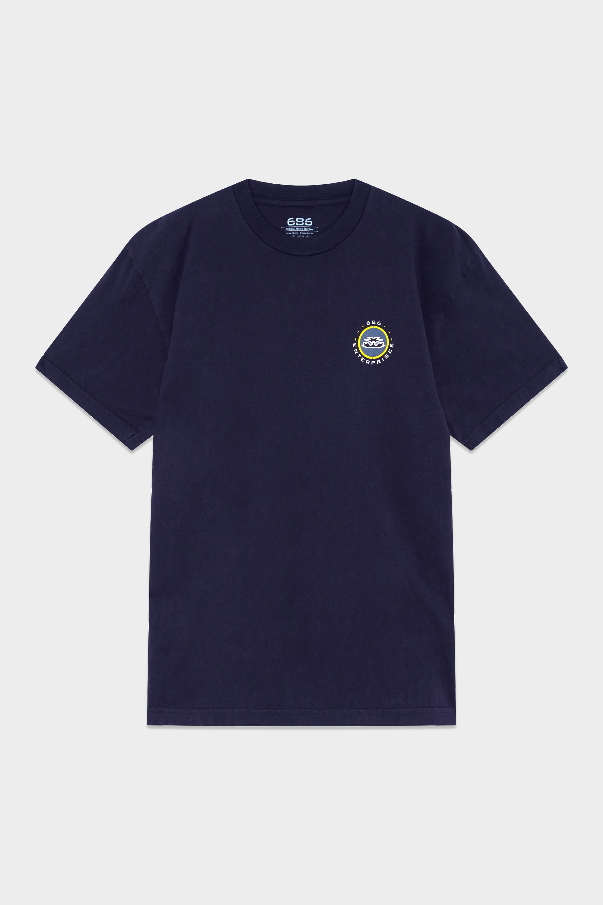 The 686 Mens Jib 2001 Badge Short Sleeve Tee is a navy blue t-shirt with a small circular logo in yellow, white, and blue on the left chest and a neckline tag displaying the 686 brand in white text.