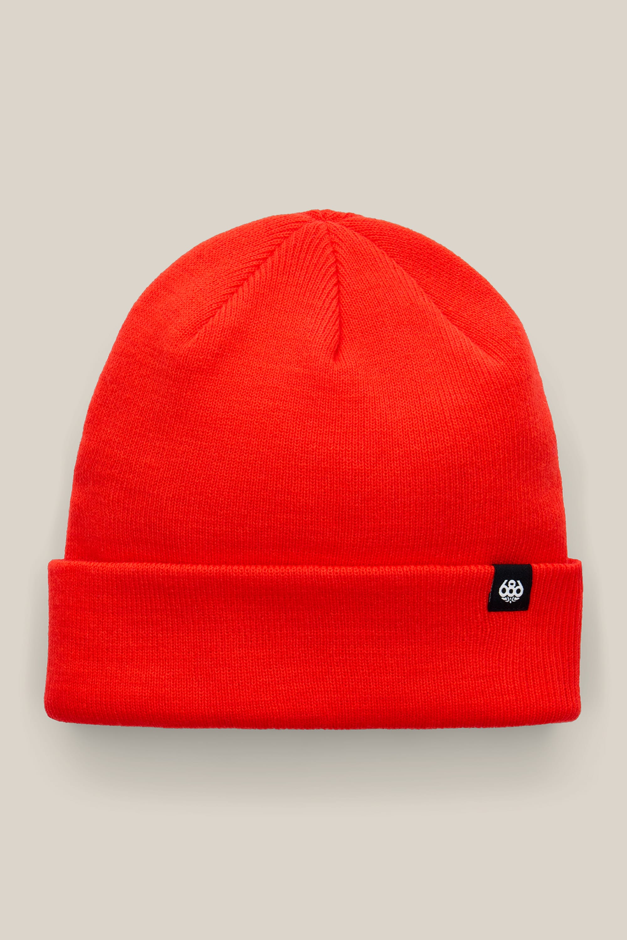 The 686 Standard Roll Up Beanie by 686 is a bright red knit hat featuring a folded brim and a small black tag with a white circular logo, shown against a plain beige background.