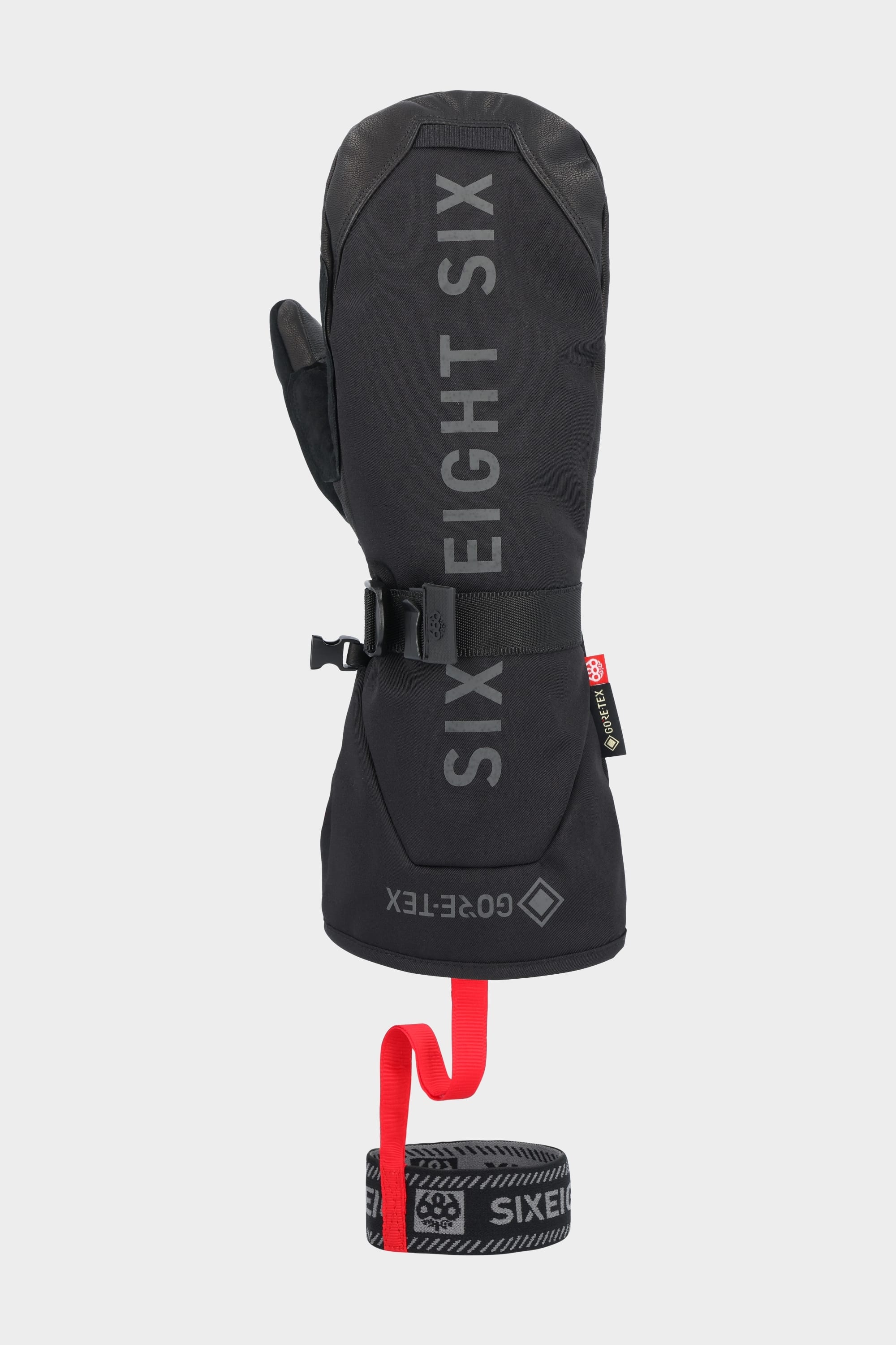 The 686 Mens GORE-TEX Leather Deep Days Mitt is a black leather mitt with GORE-TEX waterproofing, a wrist cinch buckle, and a detachable wrist leash featuring a red strap and black branded band.