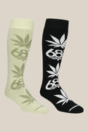 The 686 HUF Socks - 2 Pack by 686 features knee-high men’s socks in light green and black, each with a bold leaf and 68 graphic, shown side by side on a beige background—ideal for standout style and performance.