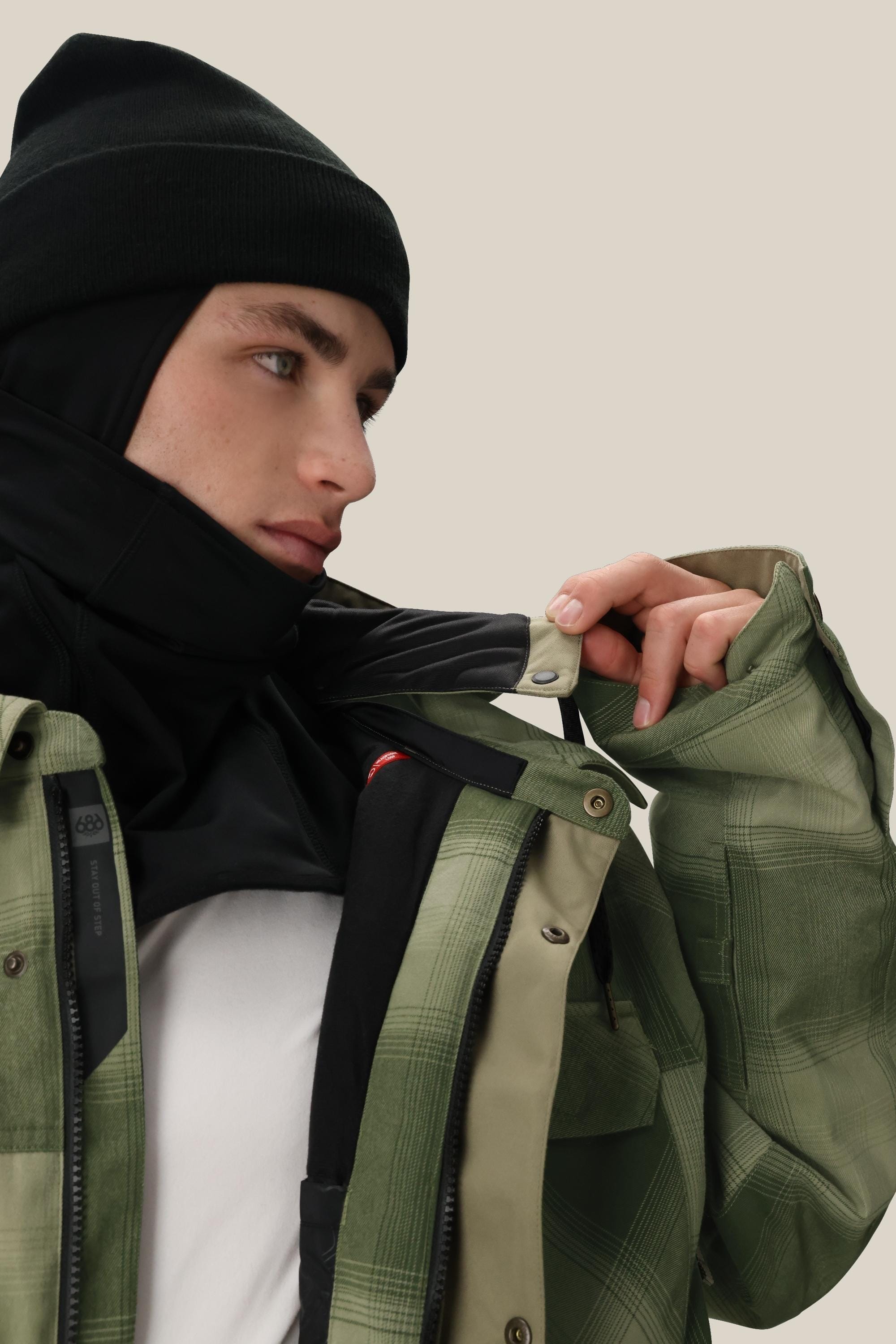 A man wearing a hat, scarf, and the 686 Mens Woodland Insulated Jacket by 686.