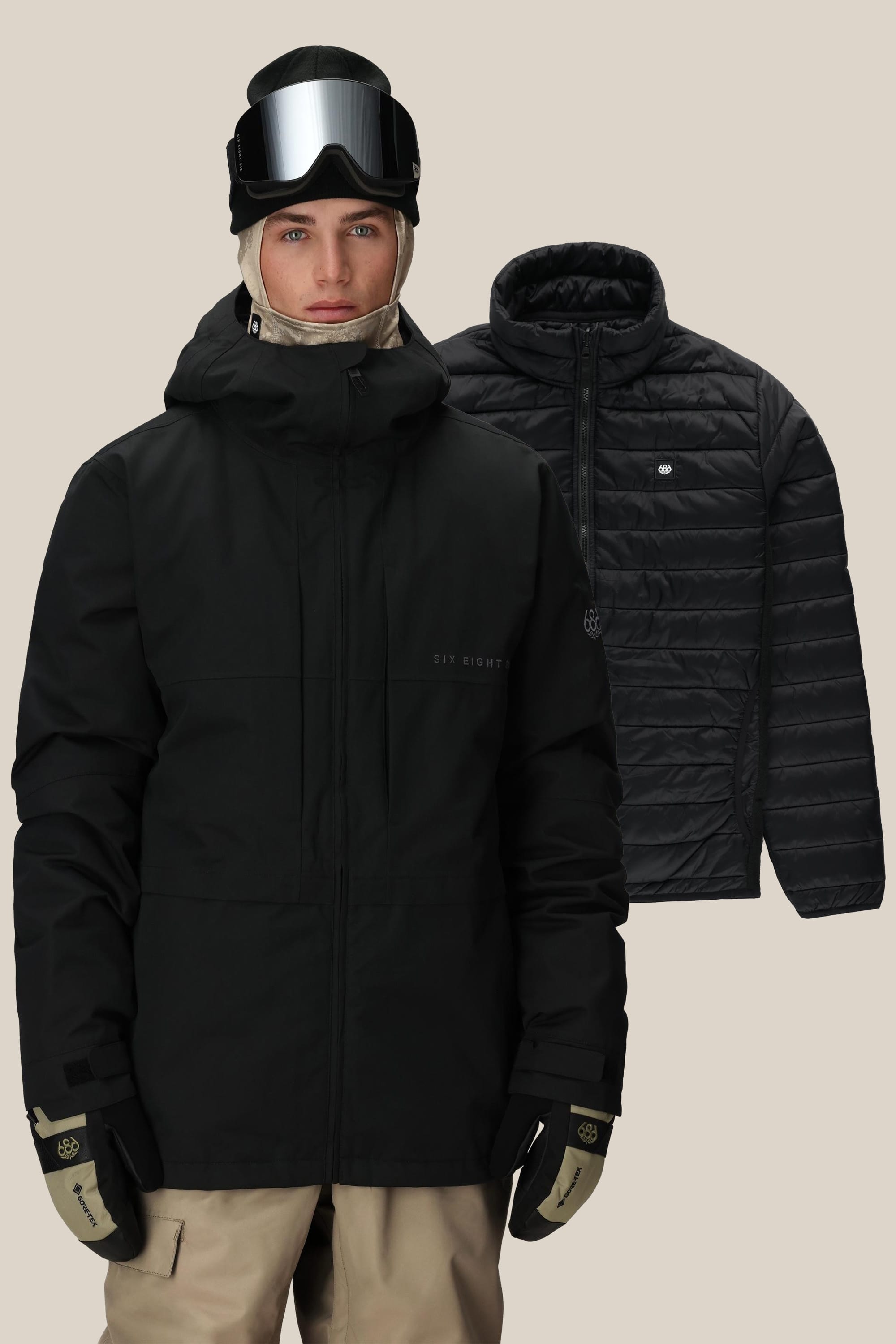 A person wearing beige pants and the 686 Men’s SMARTY® 3-In-1 Form Jacket in black, paired with gloves, goggles, and a beanie. Behind them, another matching black jacket from 686 is displayed against a plain light background.