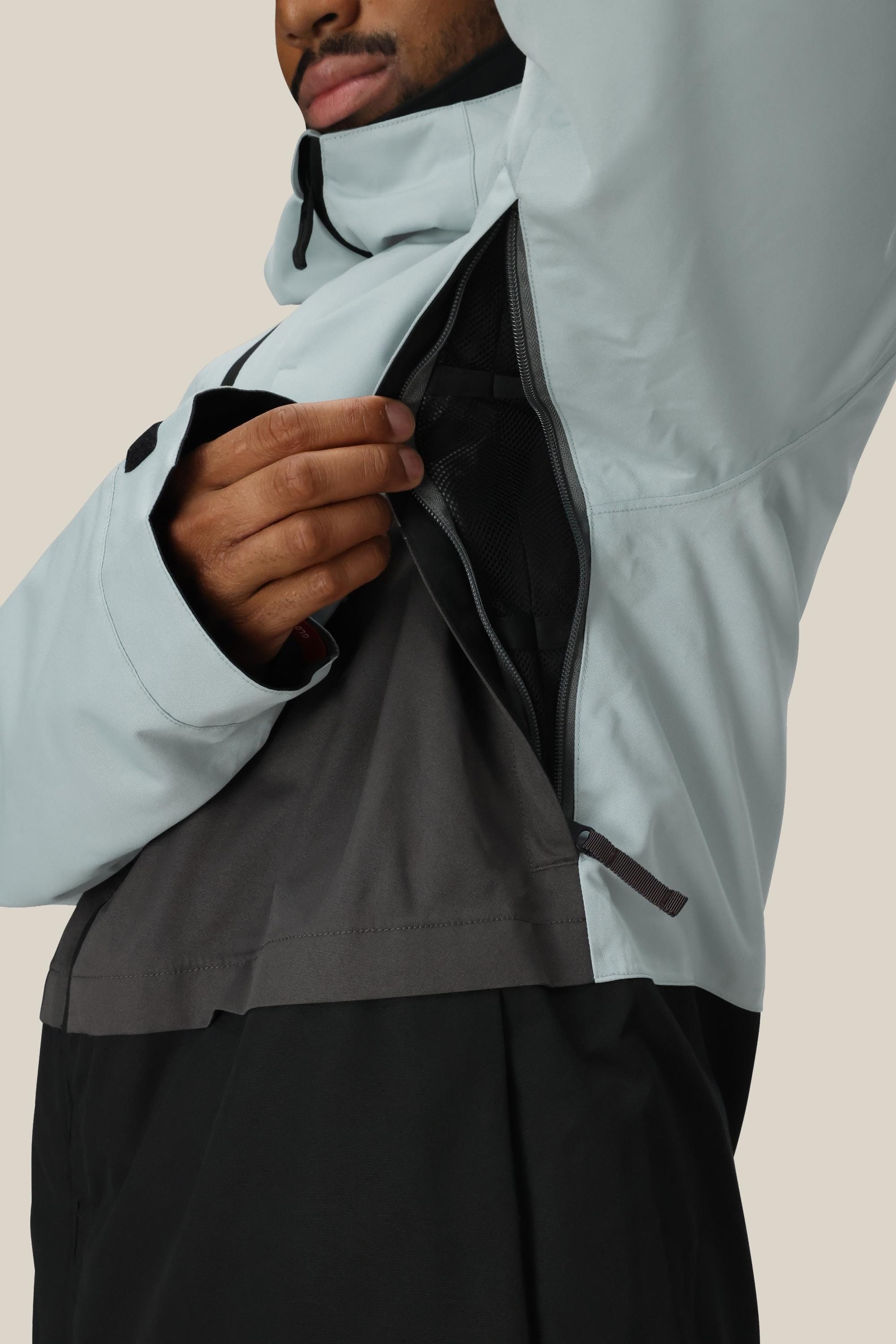 A person wearing the 686 Mens Smarty 3-In-1 Form Jacket in light gray and black unzips a large underarm vent, revealing the mesh lining inside this waterproof jacket by 686.