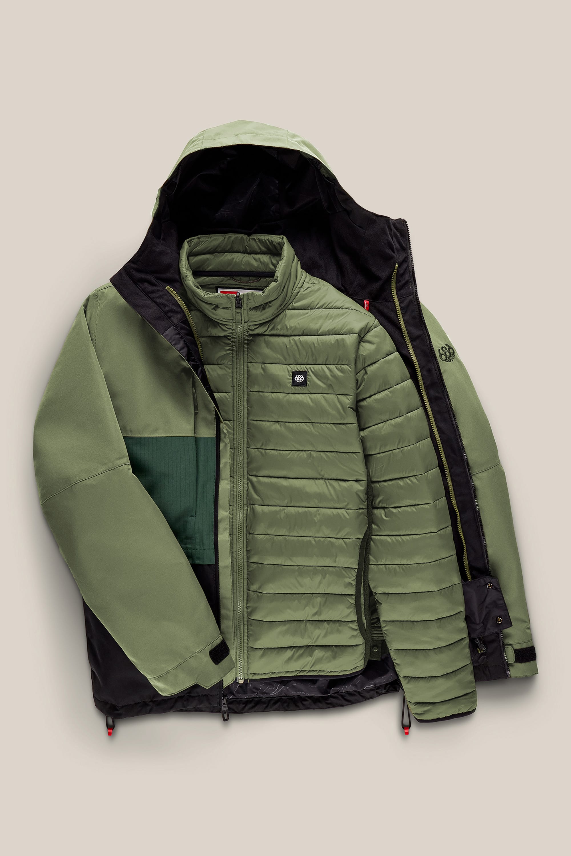 The 686 Men’s SMARTY® 3-In-1 Form Jacket by 686 is displayed laid flat, unzipped to show a lighter green quilted inner jacket. Both layers feature zippers and subtle logo patches on the chest.