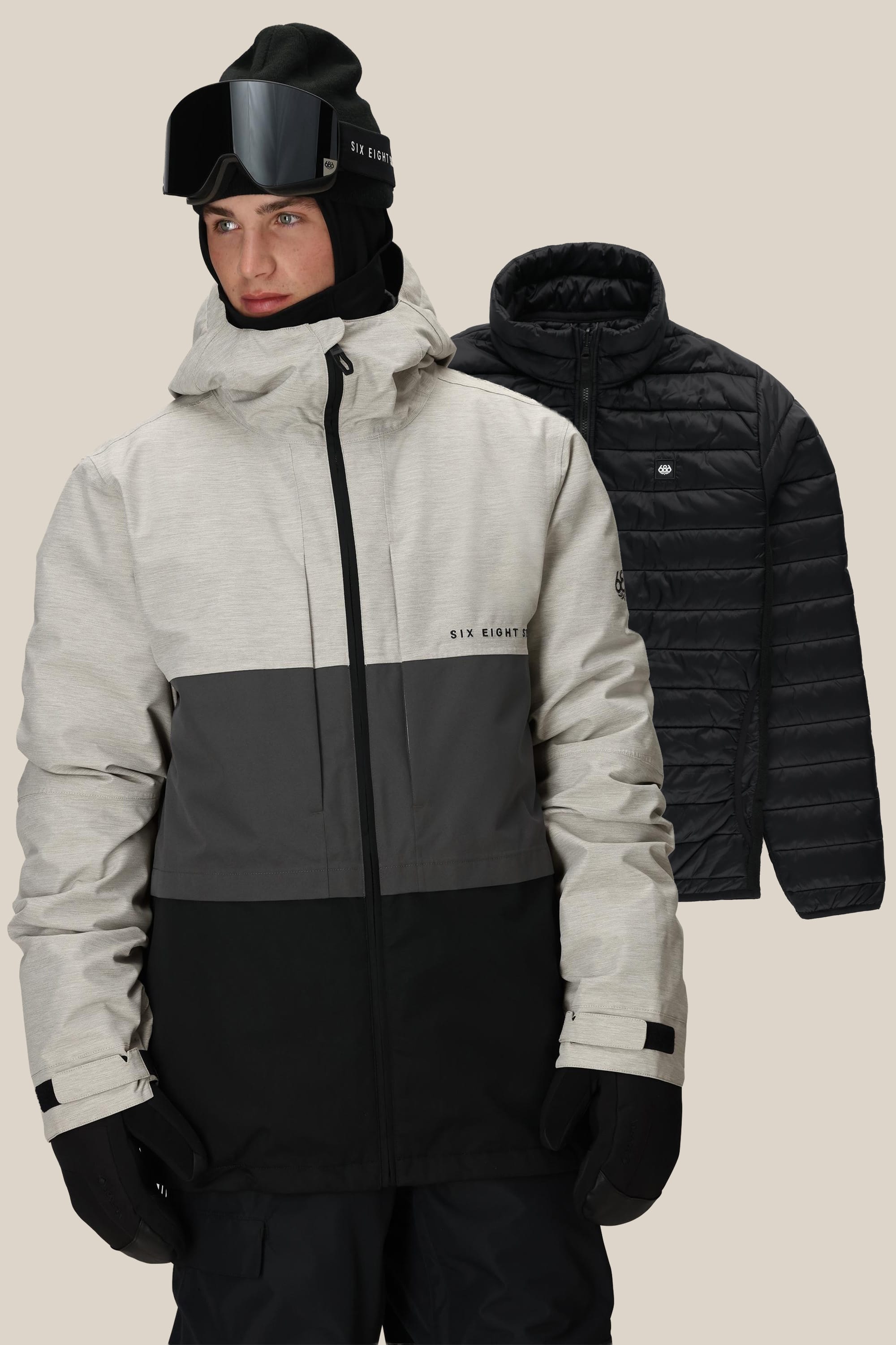 A person wearing the 686 Mens Smarty 3-In-1 Form Jacket, black gloves, ski goggles, and a beanie stands in front of a black quilted polyester jacket against a plain background.