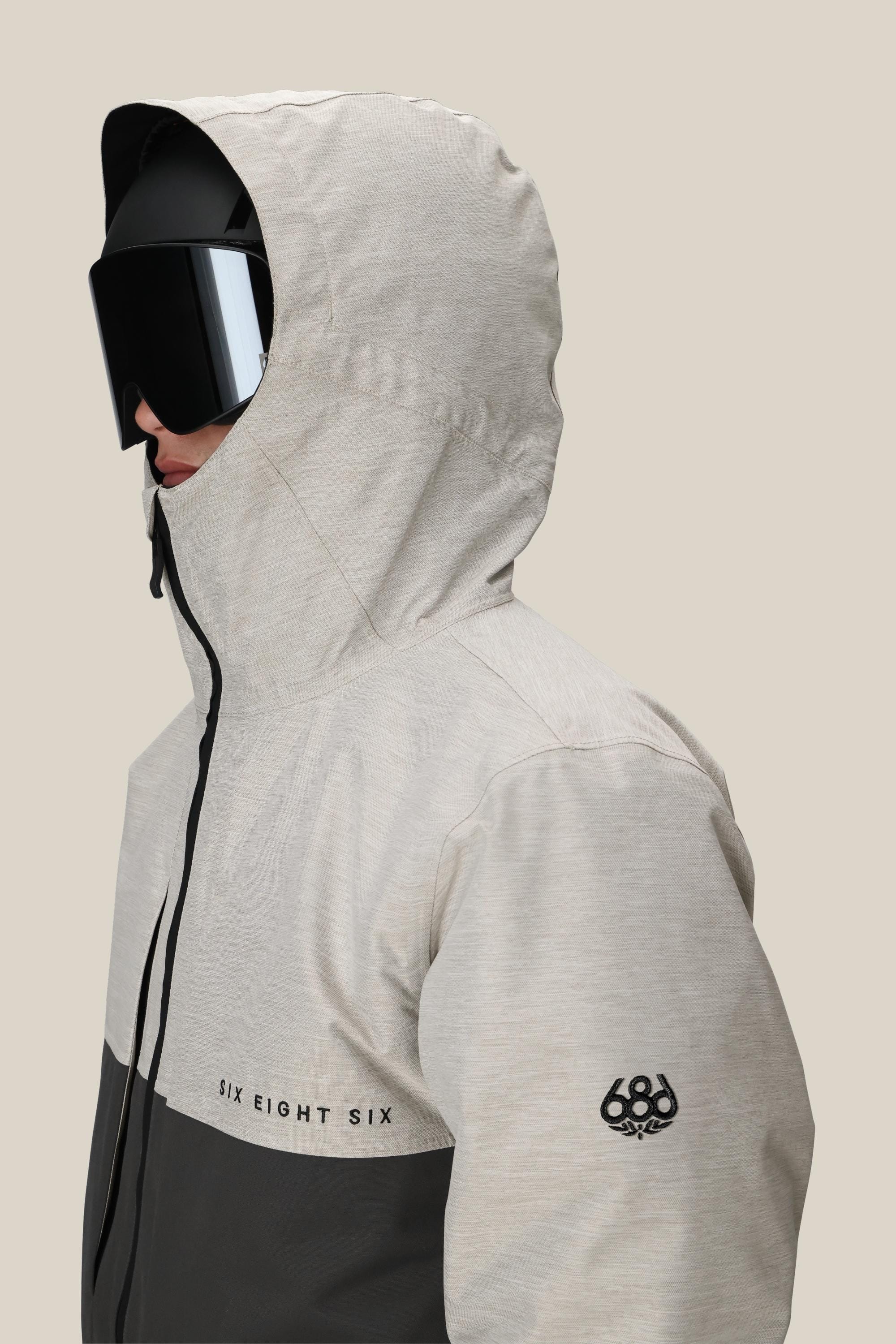 A person wearing the 686 Mens Smarty 3-In-1 Form Jacket in light gray and black, featuring the 686 logo, pairs it with large black ski goggles against a plain beige background.
