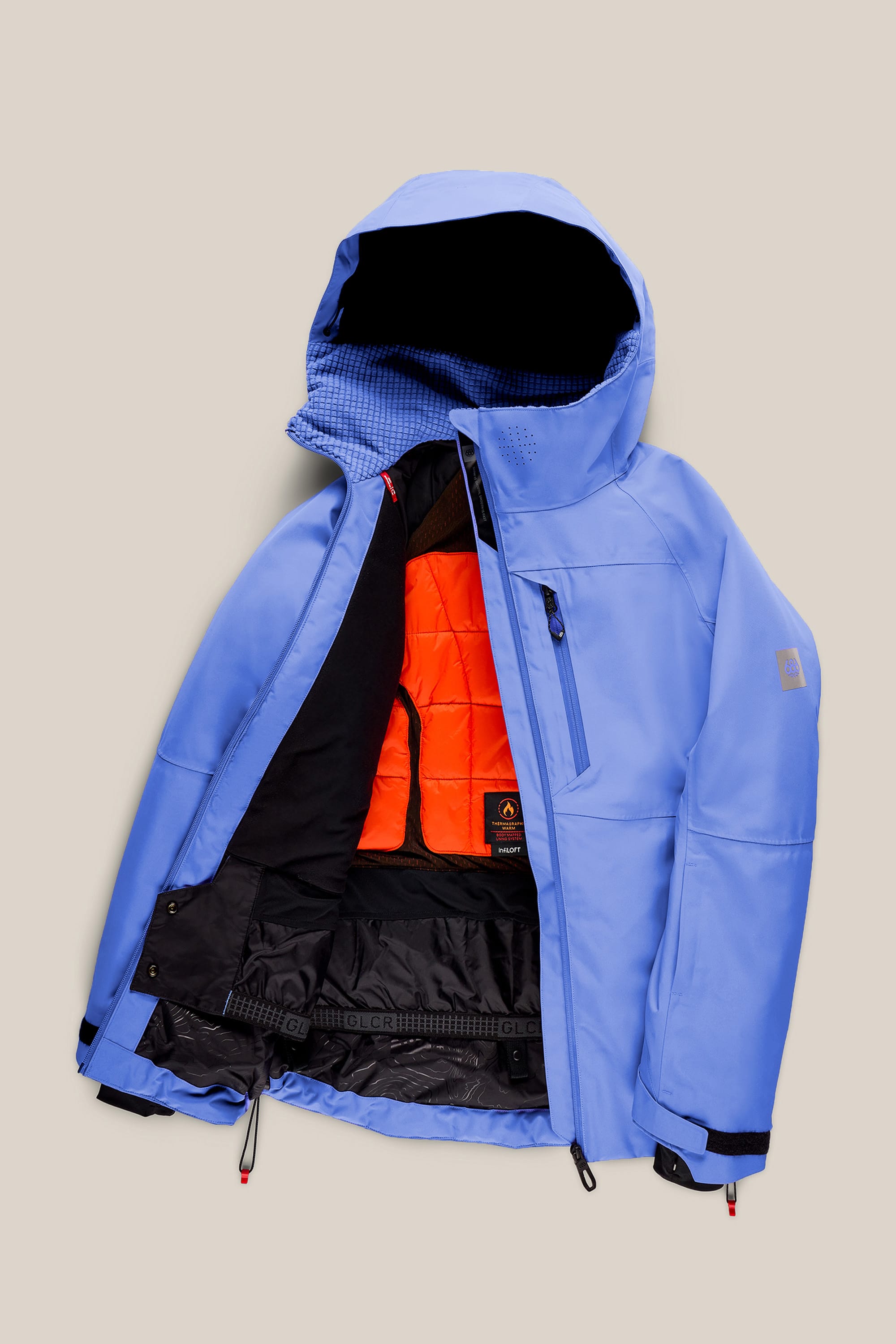 The 686 Women’s Hydra™ Thermagraph® Jacket by 686 is shown open on a beige background, featuring a light blue exterior, orange inner lining, black interior panels, a chest zipper pocket, and adjustable wrist straps.