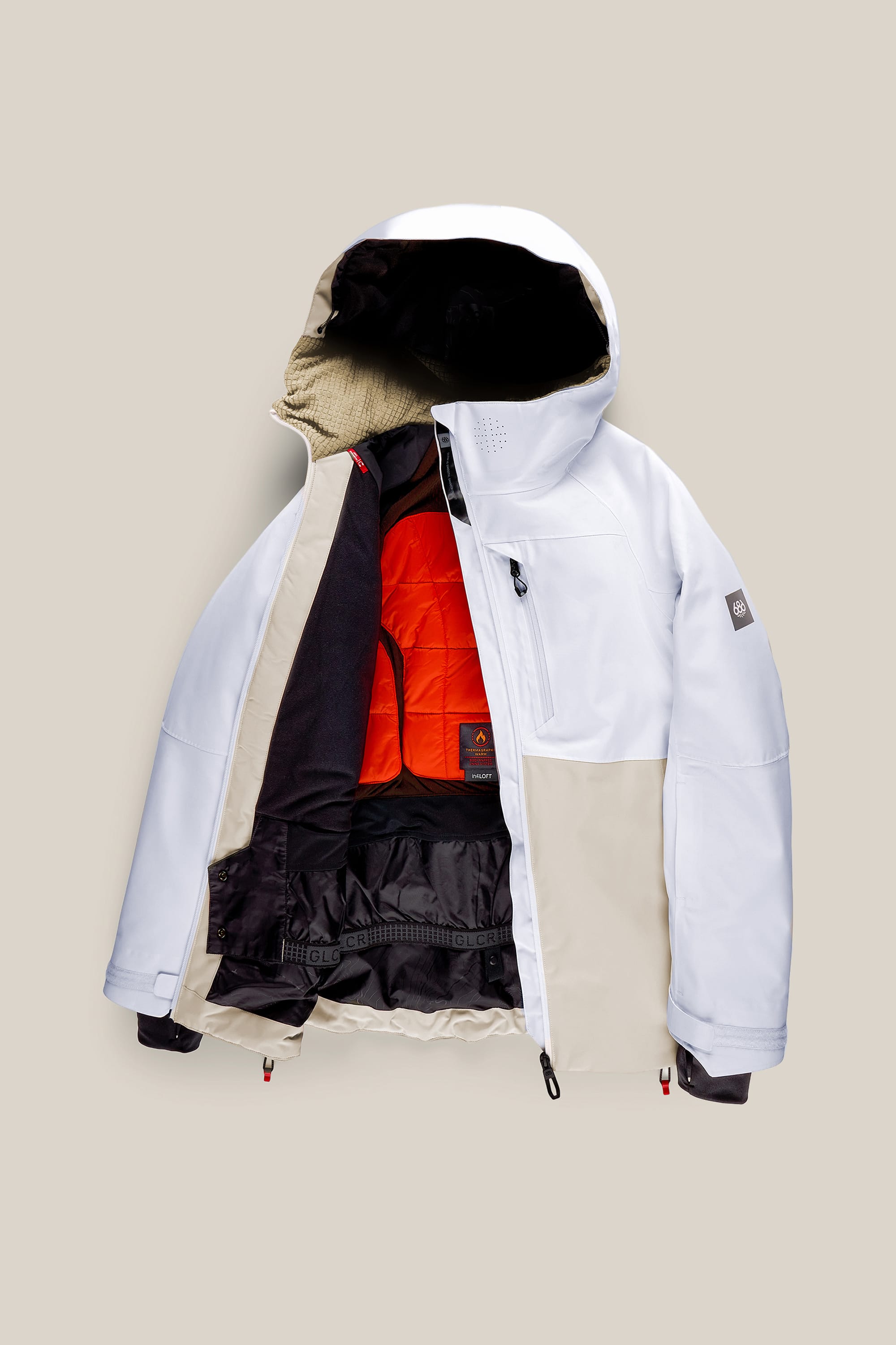 The 686 Women’s Hydra™ Thermagraph® Jacket by 686 is a white and beige winter jacket with a hood, shown open to reveal a bright orange quilted lining and multiple black inner layers, displayed on a light beige background.