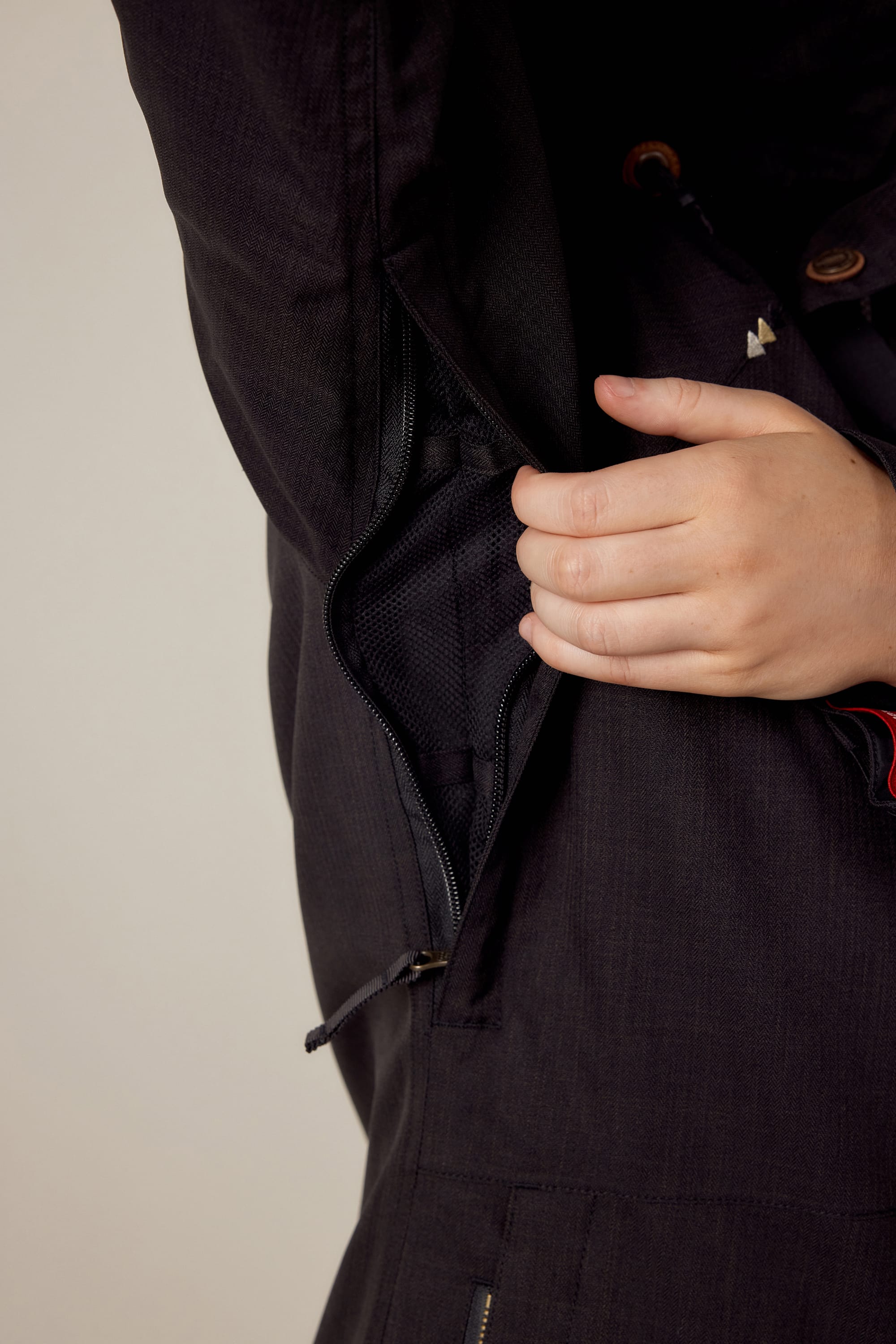 A person unzips a hidden side zipper on the 686 Womens Smarty 3-In-1 Spellbound Jacket, revealing its mesh-lined interior.