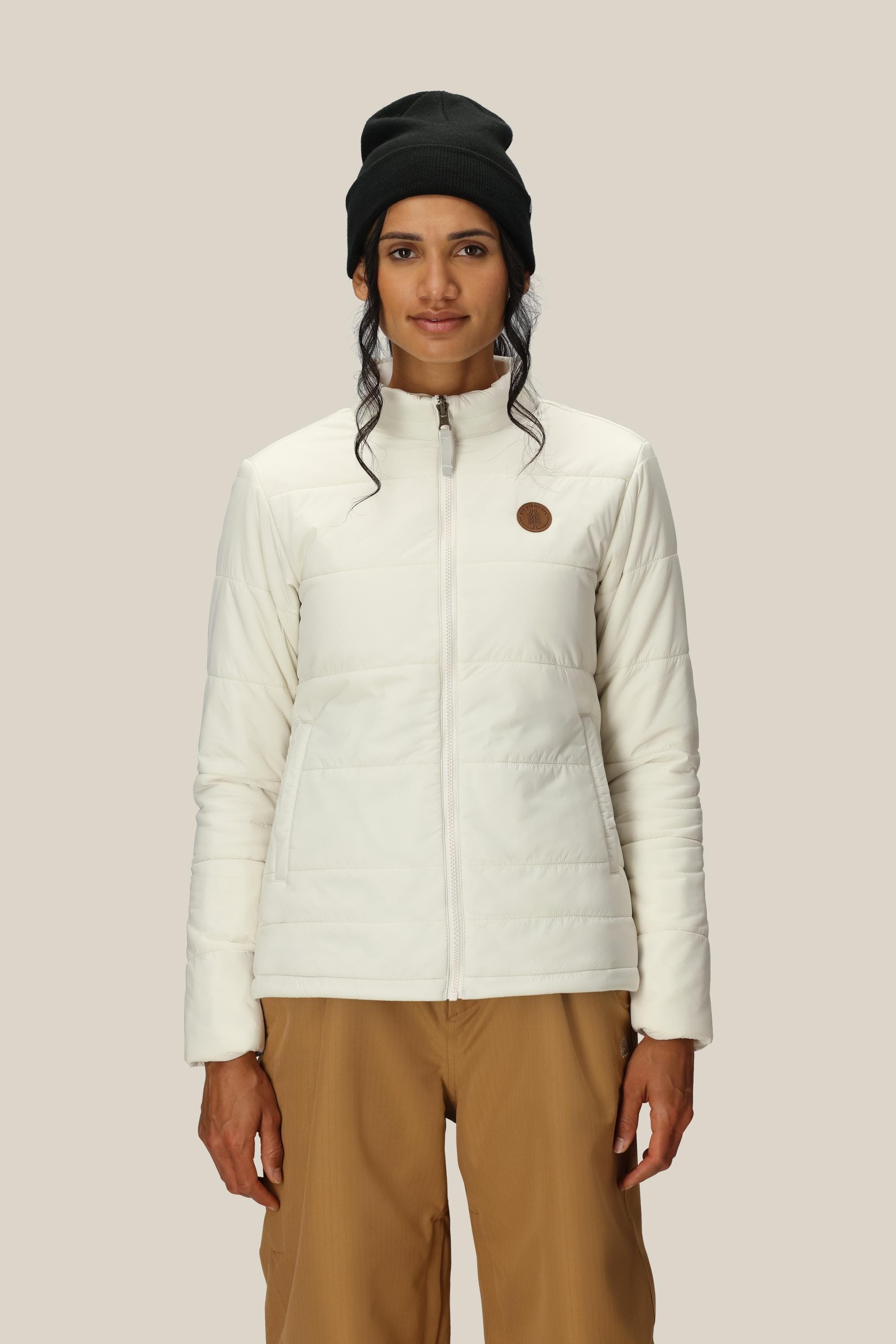 A person wearing the 686 Womens Smarty 3-In-1 Spellbound Jacket, tan pants, and a black beanie stands facing forward against a plain light beige background.