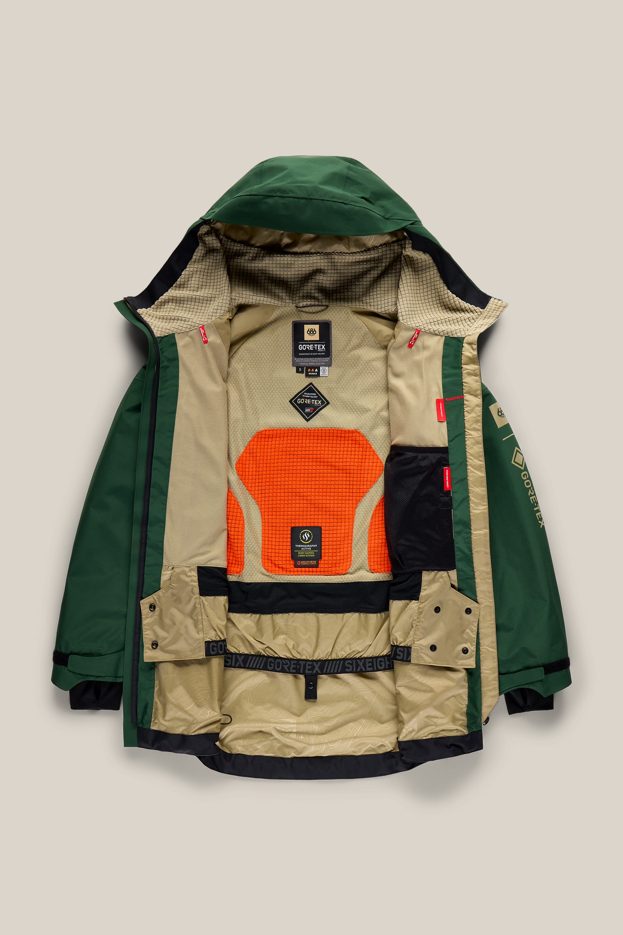 The 686 Women’s GORE-TEX® Skyline Thermagraph® Jacket by 686 is displayed flat with its front open, showcasing a mesh orange lining, black labels, multiple inner pockets, and GORE-TEX branding on the inner waist and sleeves. The jacket features a green and tan colorway with an attached hood.